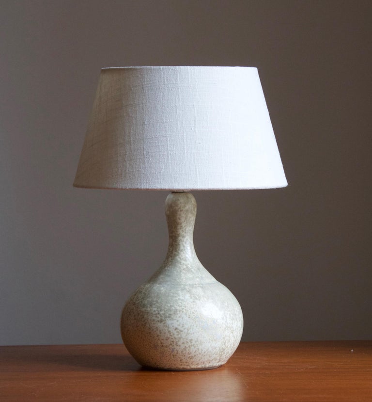 A table lamp. In glazed stoneware. Stamped to bottom. With label indicating it's a hand-crafted studio piece.

Stated dimensions exclude lampshade. Height includes socket. Sold without lampshade.

Glaze features a white-grey color.