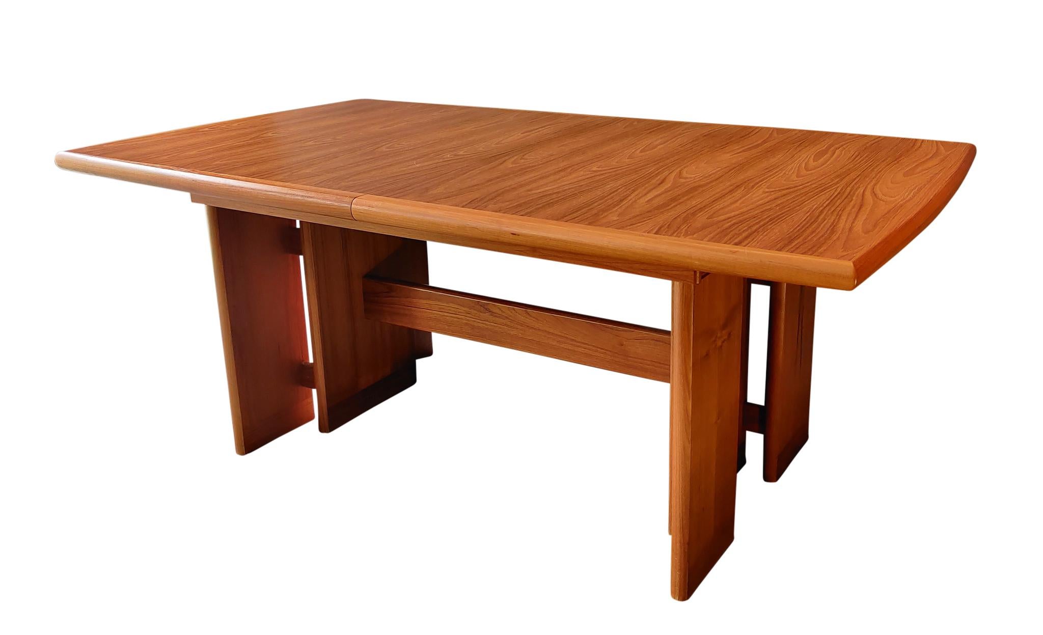 A fantastic large Danish style teak dining table by Nordic Furniture, Canadian made, from the late 1970s or early 1980s. A boat shaped table-top, with fine teak grain that's book-matched, on strong pairs of slab like and very architectural legs - so