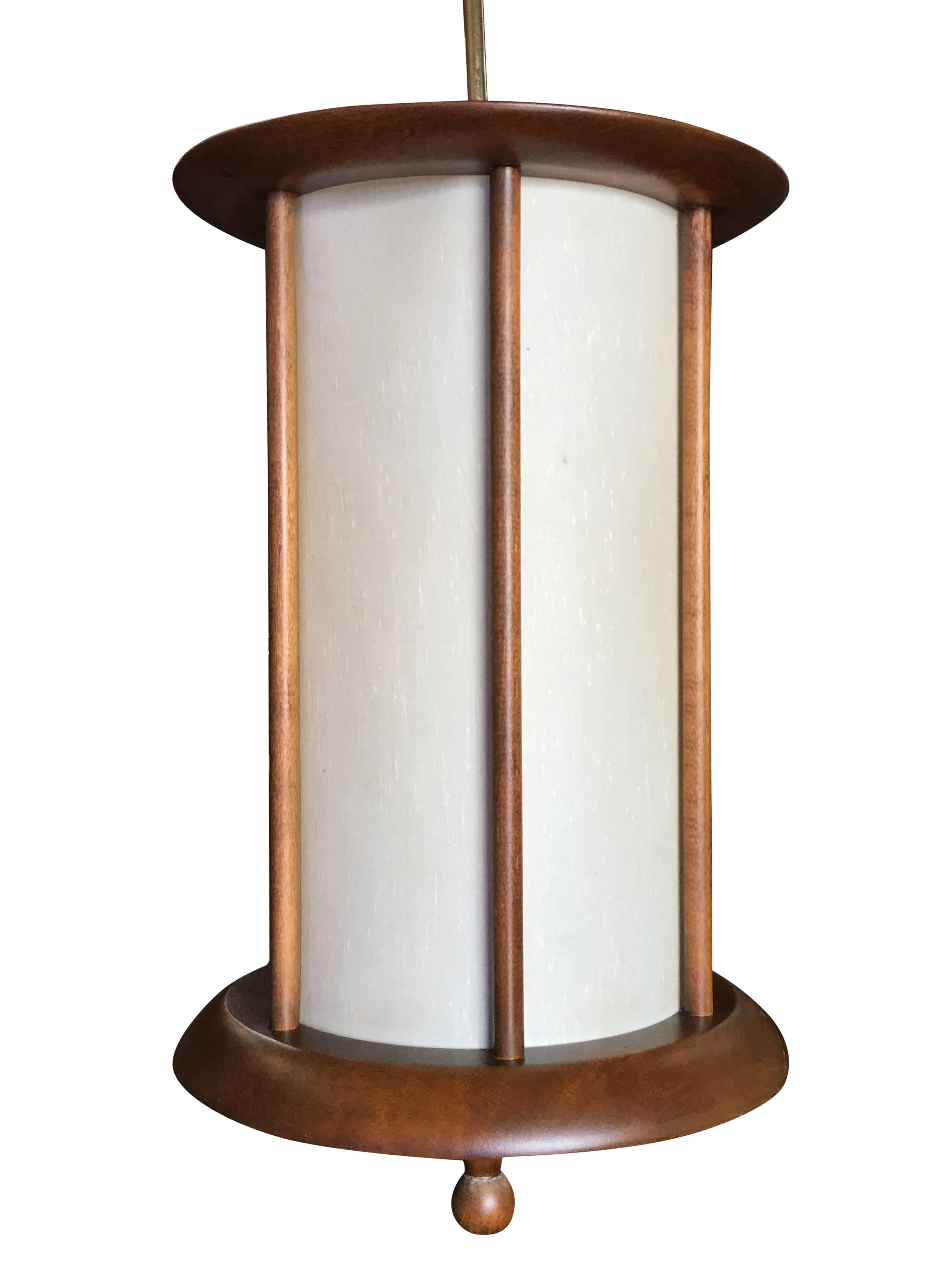 Danish style Mid-Century walnut cylinder pendant with fabric shade and brass hanging rod. This piece is a perfect compliment to a modernist home with its simple lines, elegant stance and earthy combination of brass, walnut, and fabric.