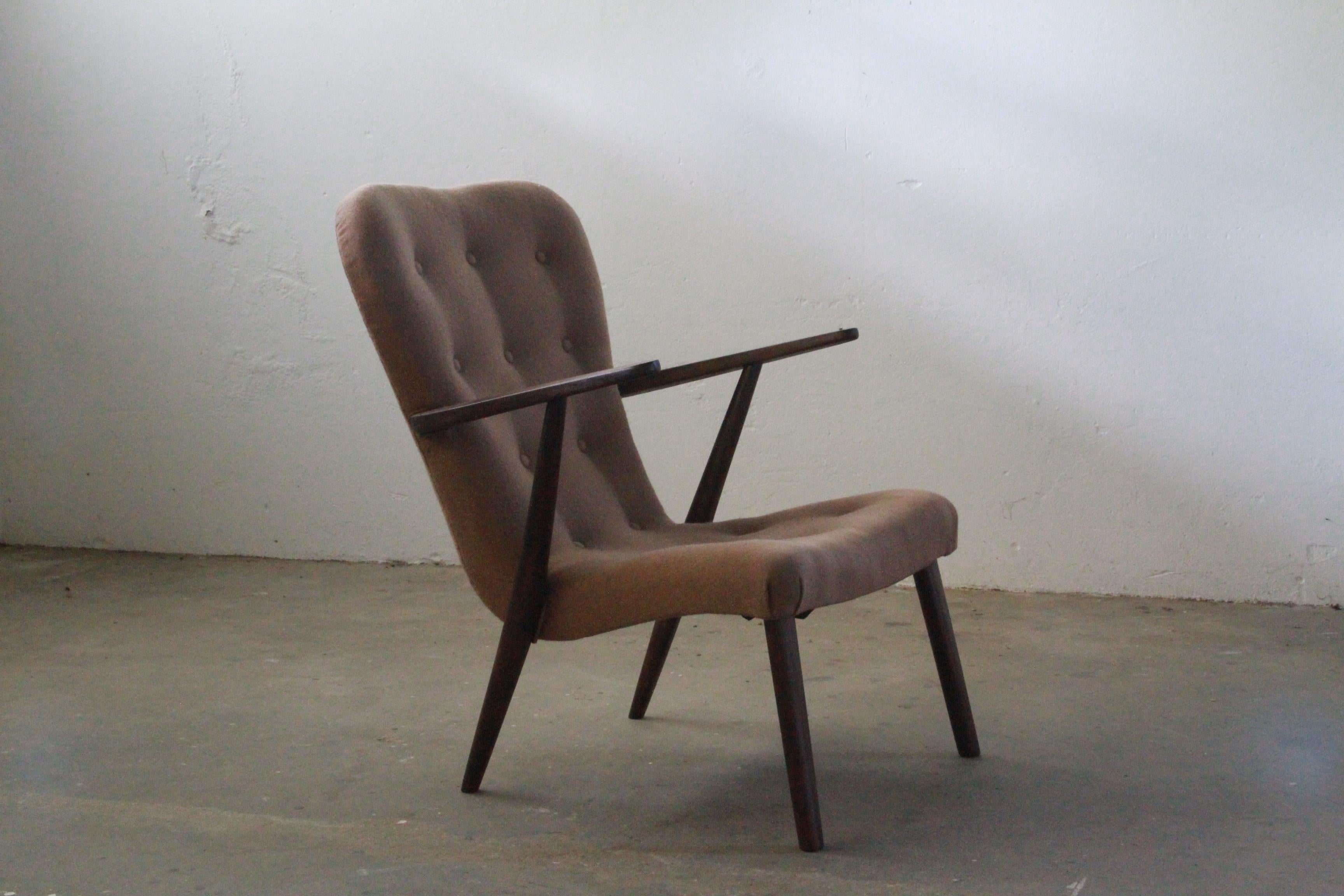 This exquisite lounge chair, crafted in Denmark, boasts a striking charm, thanks to its stained and varnished beech wood construction. Its design is reminiscent of two iconic chairs: the renowned Pragh chair by Schubell and Madsen and the elegant