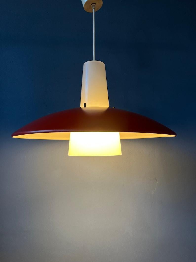 Lampada a sospensione in stile danese di Louis Kalff per Philips. Il paralume rosso è in metallo e il paralume bianco traslucido è in plastica. La lampada richiede una lampadina E27/26 (standard).

Informazioni aggiuntive:
Materiale: Metallo,