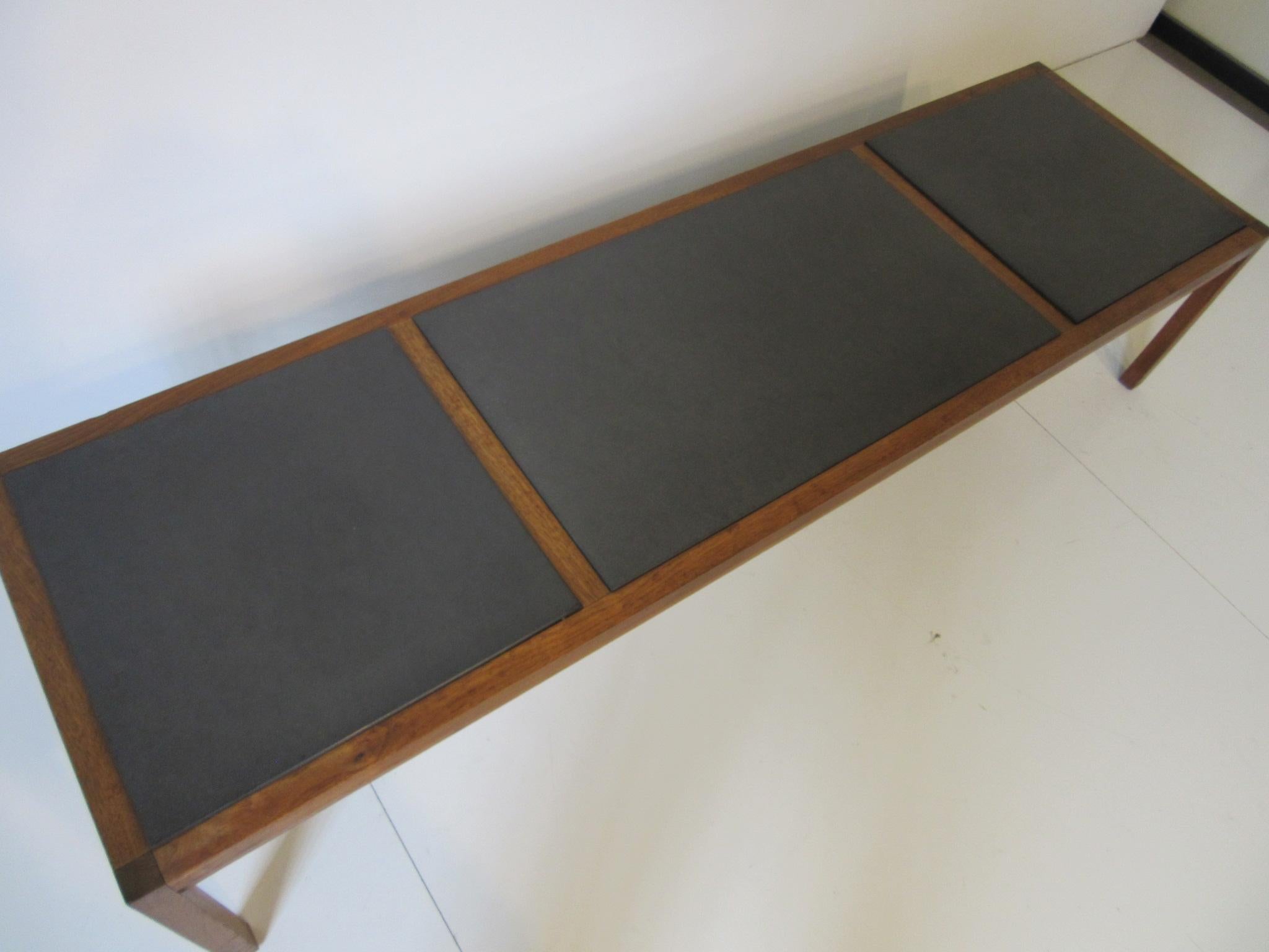 A walnut framed Parsons styled coffee table with three charcoal colored slate inserts constructed in the style of Danish modern.