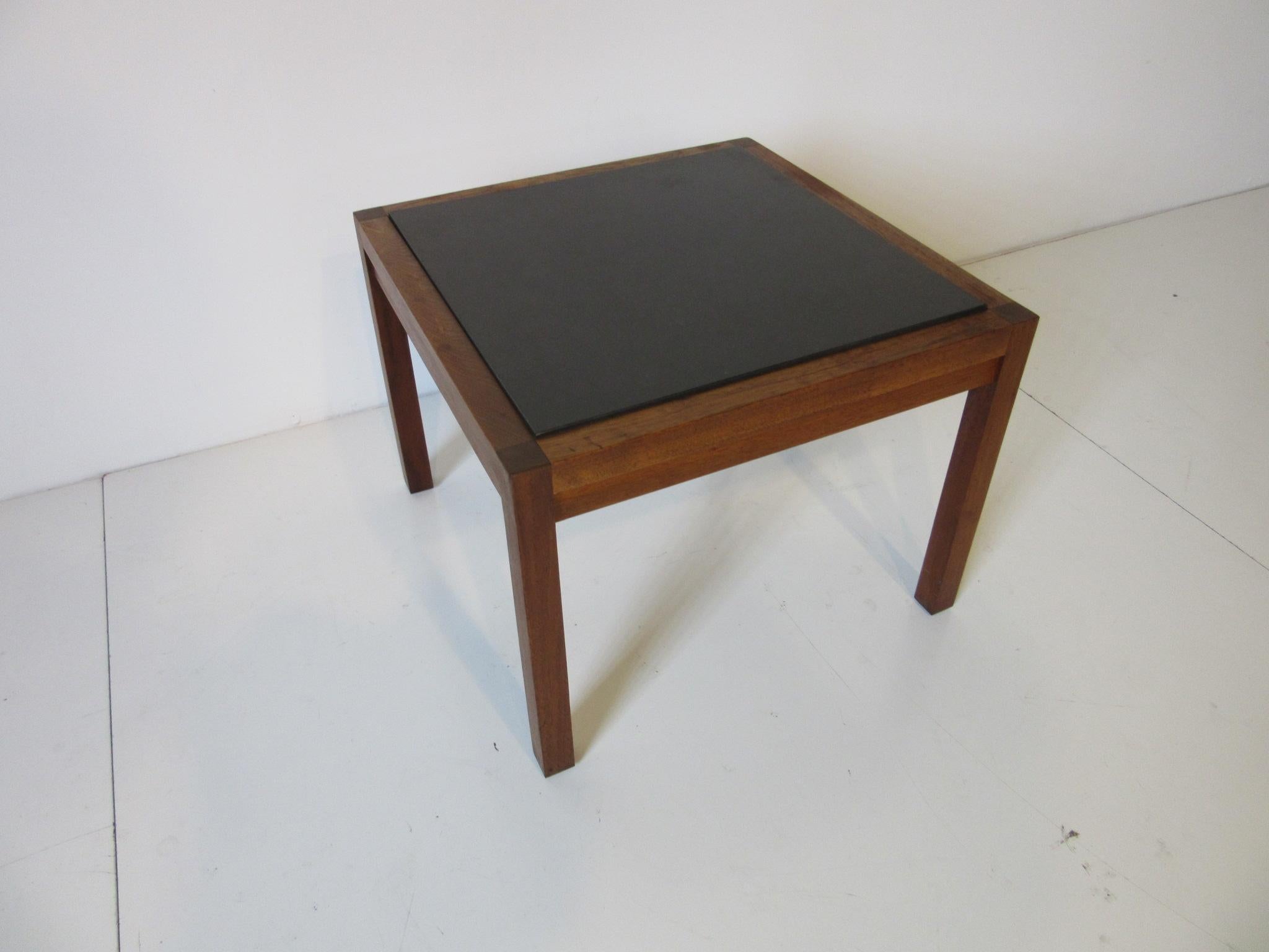 A Parsons styled walnut framed side table with a charcoal colored slate inserts in the style of Danish modern.