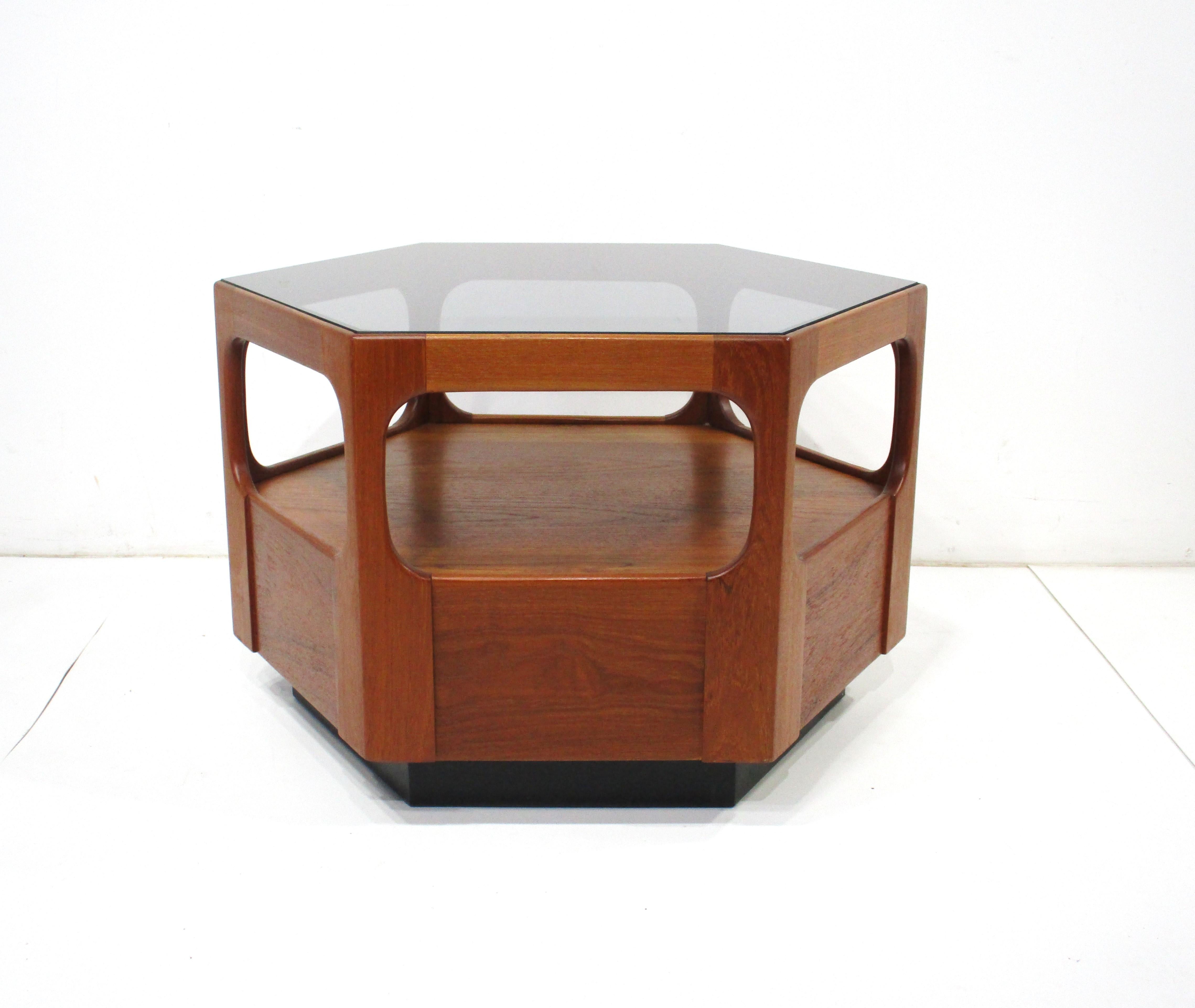 A well crafted walnut octangular and inset smoked glass smaller scale coffee table or can be used as a corner table . With the lower shelve area for extra storage making the piece very useful , manufactured by the cabinetmaker Otmar in the tradition