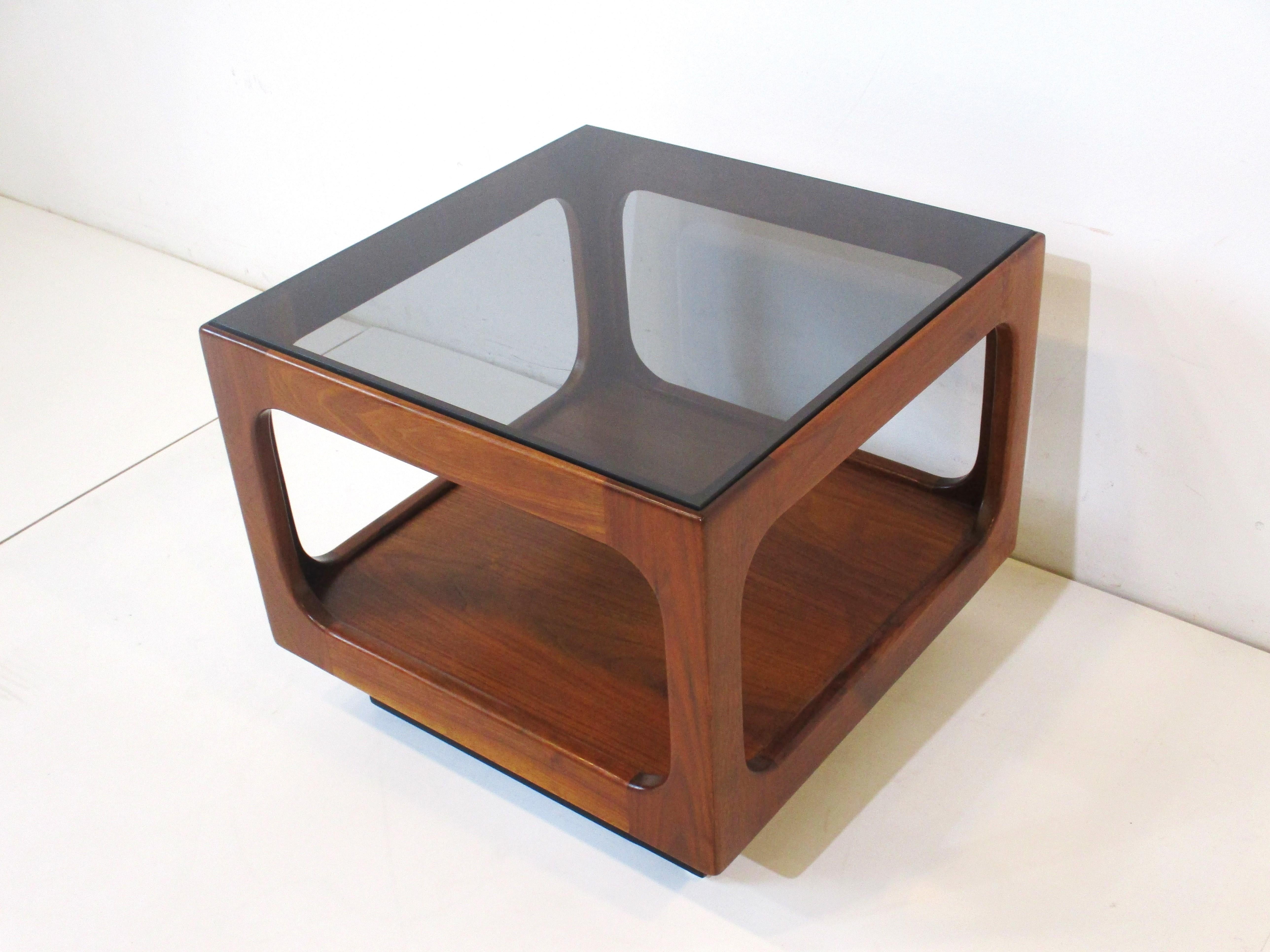 A very well crafted Danish styled walnut Cube side table with a lightly smoked glass top. Having a lower storage area and with the satin black kick base gives the piece a floating look and light feel. Designed and hand manufactured by Otmar who