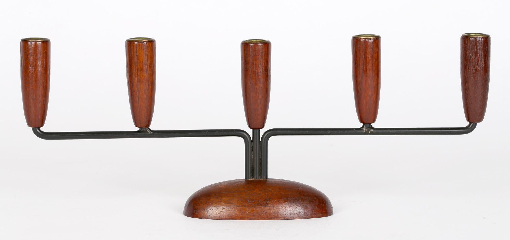 Ein schlichter, aber beeindruckender dänischer Kerzenleuchter aus Metall und Holz aus der Mitte des Jahrhunderts, um 1960. Der Kerzenständer steht auf einem geschnitzten, erhöhten, ovalen Sockel mit drei Metallarmen, die sich von der Mitte aus