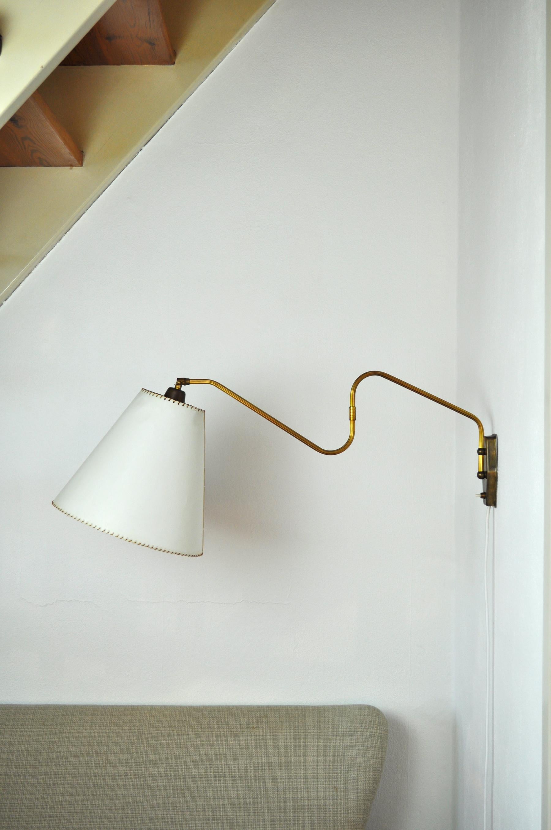 Brass wall lamp with two-piece swing arm and adjustable head.
Swivel and wall mount made in brass, mounted with original shade. 

Measures: Arm length incl. shade: circa 80 cm
Height ca. 40 cm 
Shade 11.5/29 cm, height 25 cm

Condition: Good