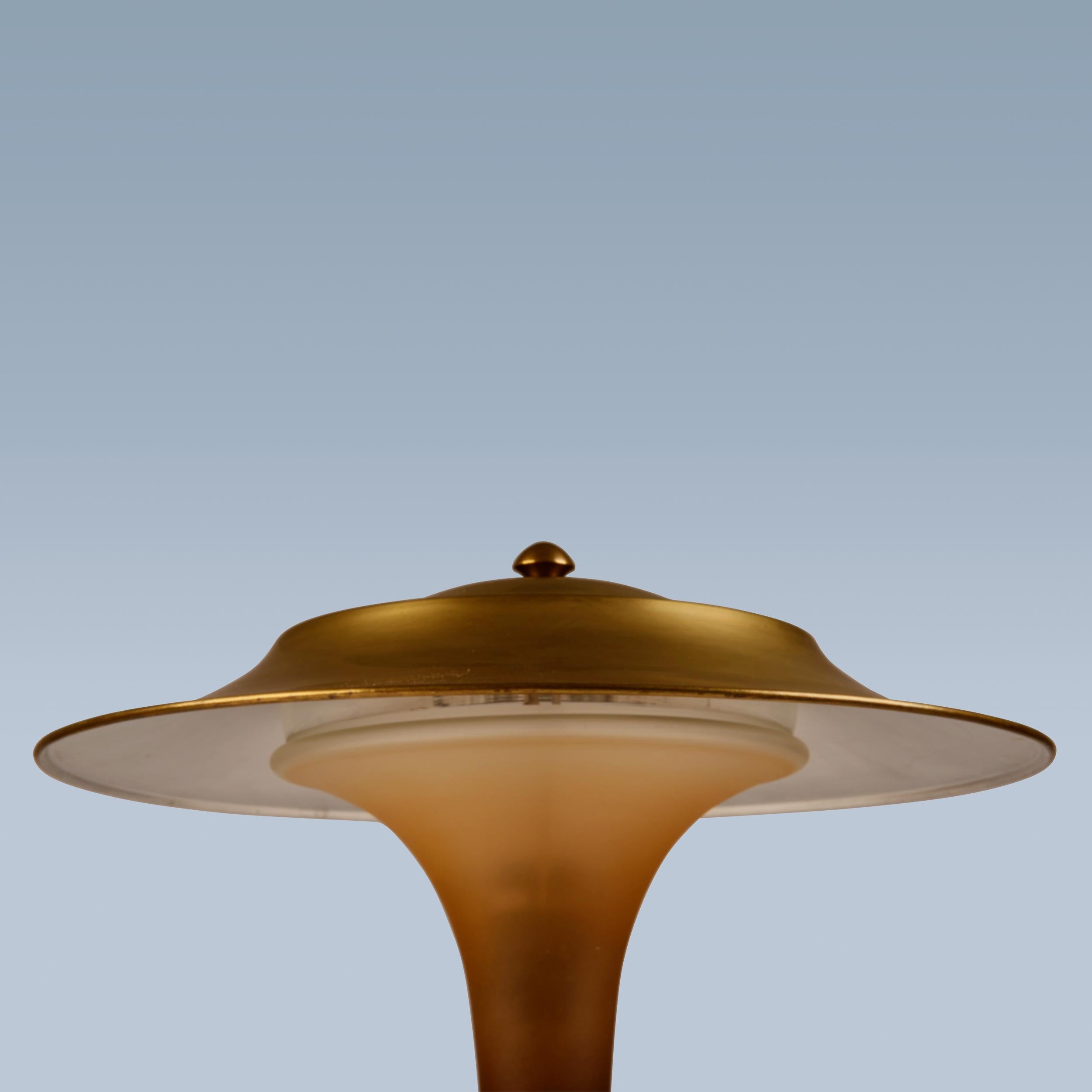 Diese Tischlampe mit Fuß aus patiniertem Messing, Schirm und Stiel aus mattiertem, bernsteinfarbenem Glas wurde von Fog & Mørup ca. in den 1930er Jahren hergestellt.
Die Lampe ist die so genannte 