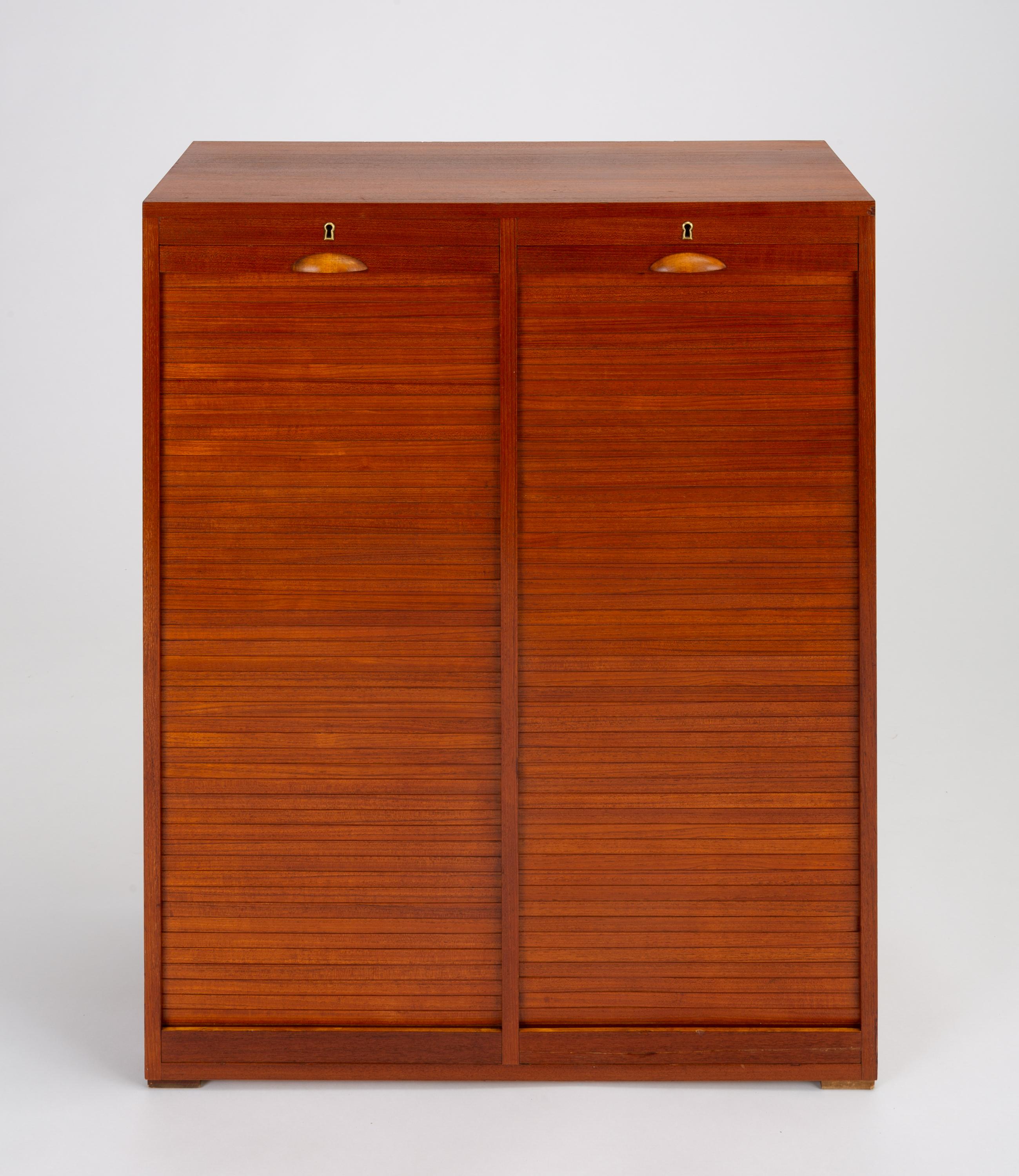 A stately teak filing cabinet with two vertical tambour doors made by Frej-Odense. Each interior space holds ten drawers of solid beech. The drawers are notched on the front panel to accommodate a label. A single skeleton key unlocks both cabinets.