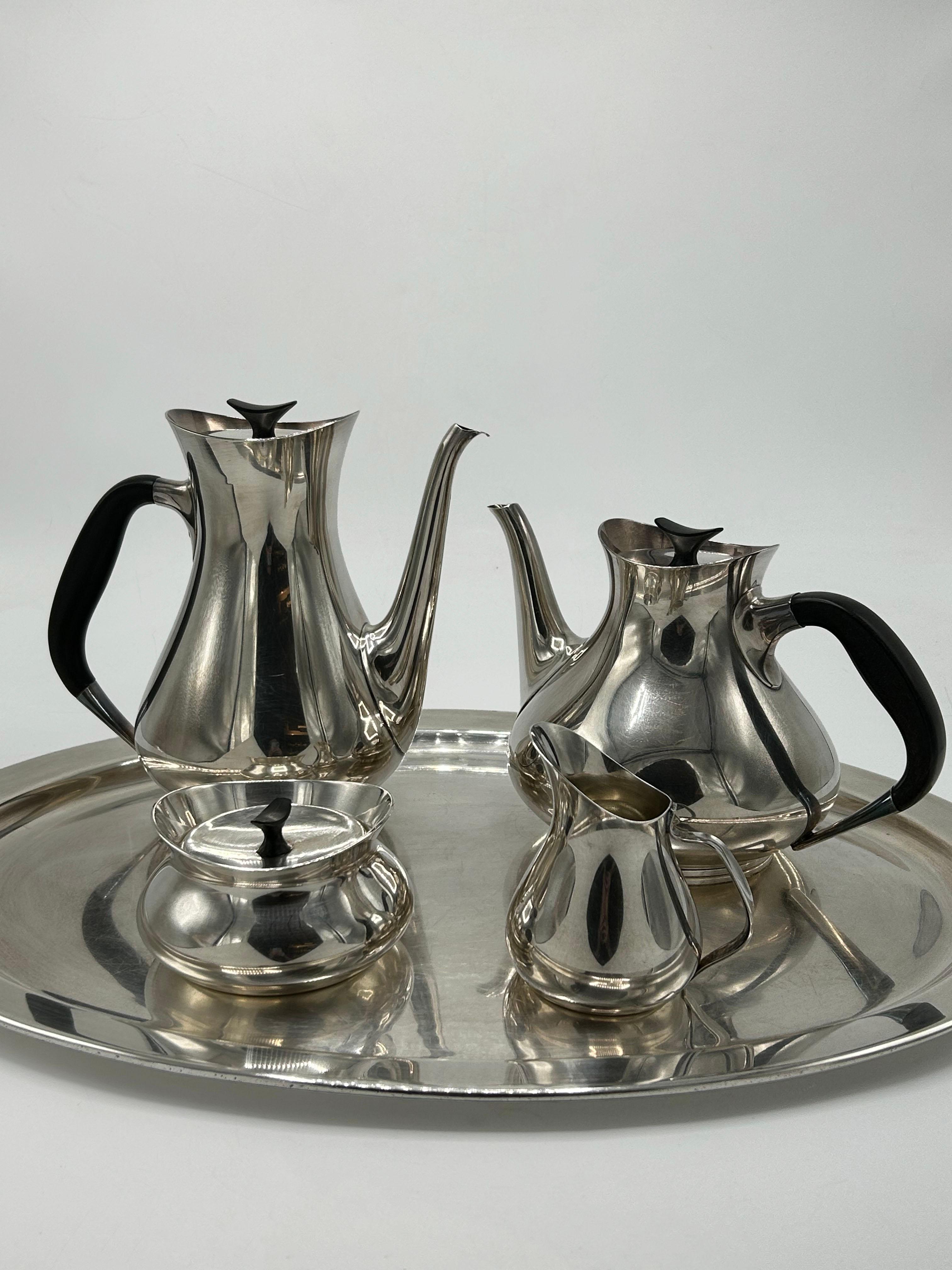 Cohr Danish Tea Set, Denmark
Elegant silver-plated tea set featuring a modern Scandinavian design, consisting of an oval tray, coffee pot, teapot, sugar bowl, and creamer. The pieces feature clean lines, soft curves, and stylized proportions, with