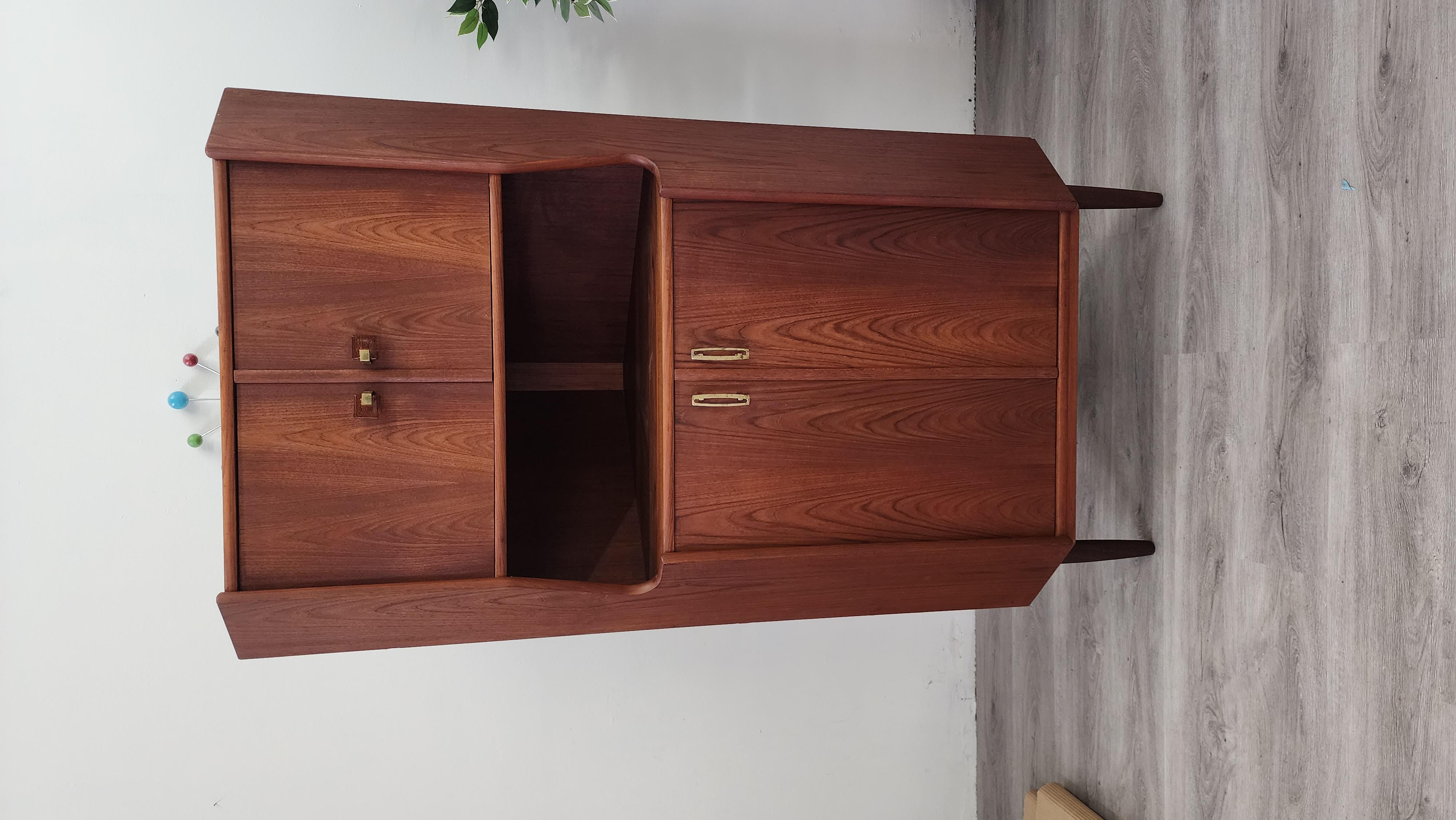 This Danish teak corner cabinet is from the 1950s. It has unique bakelite-like handles that are rarely seen on Danish pieces. This cabinet was just recently purchased from the original owner in Denmark and imported to the US. It has been