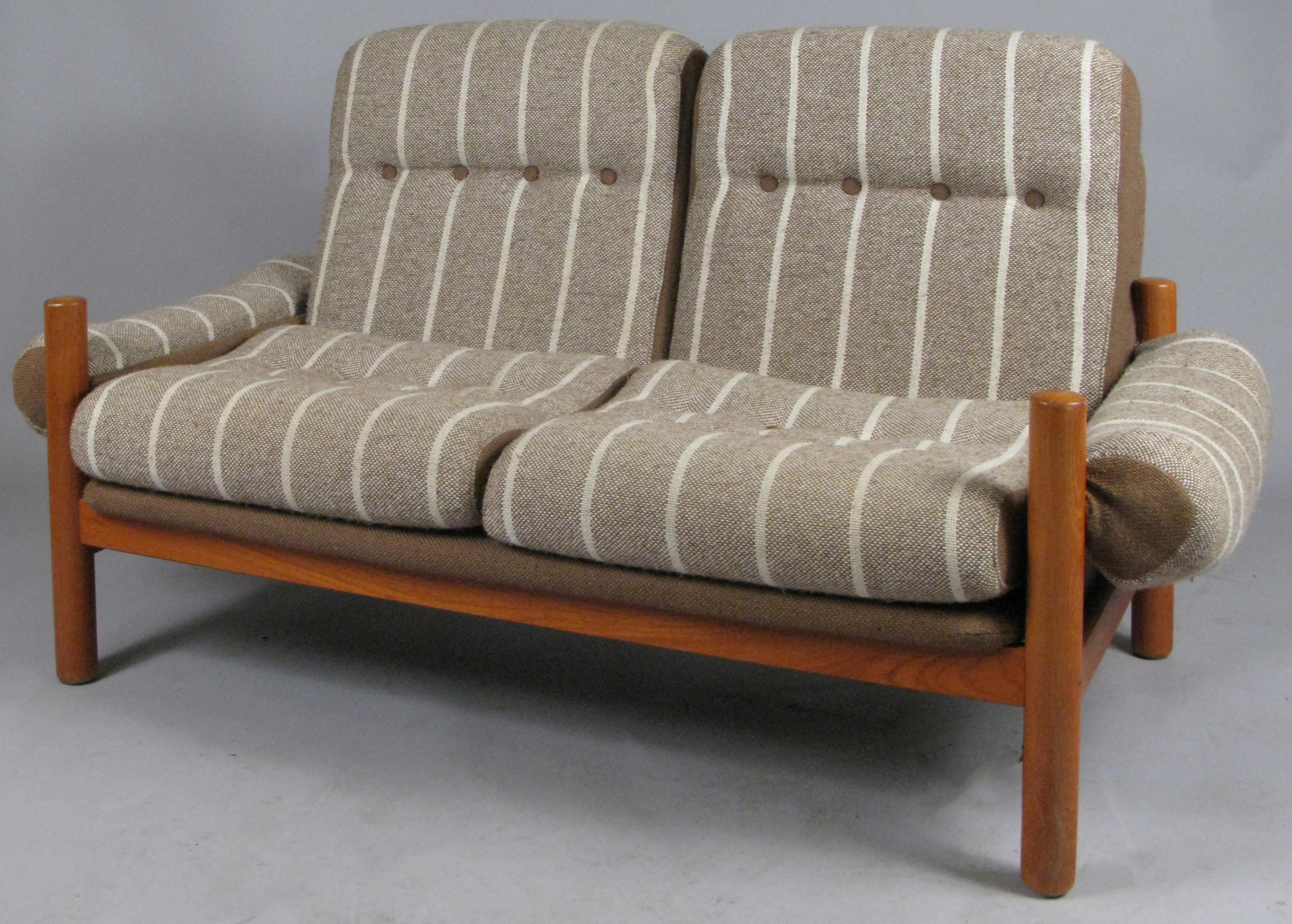 A very handsome solid teak vintage 1970s two-seat settee made by Domino Mobler. With it's original brown linen covered seat frames, and newly upholstered seat, back, and arm cushions in a woven beige and cream. Very stylish and comfortable.