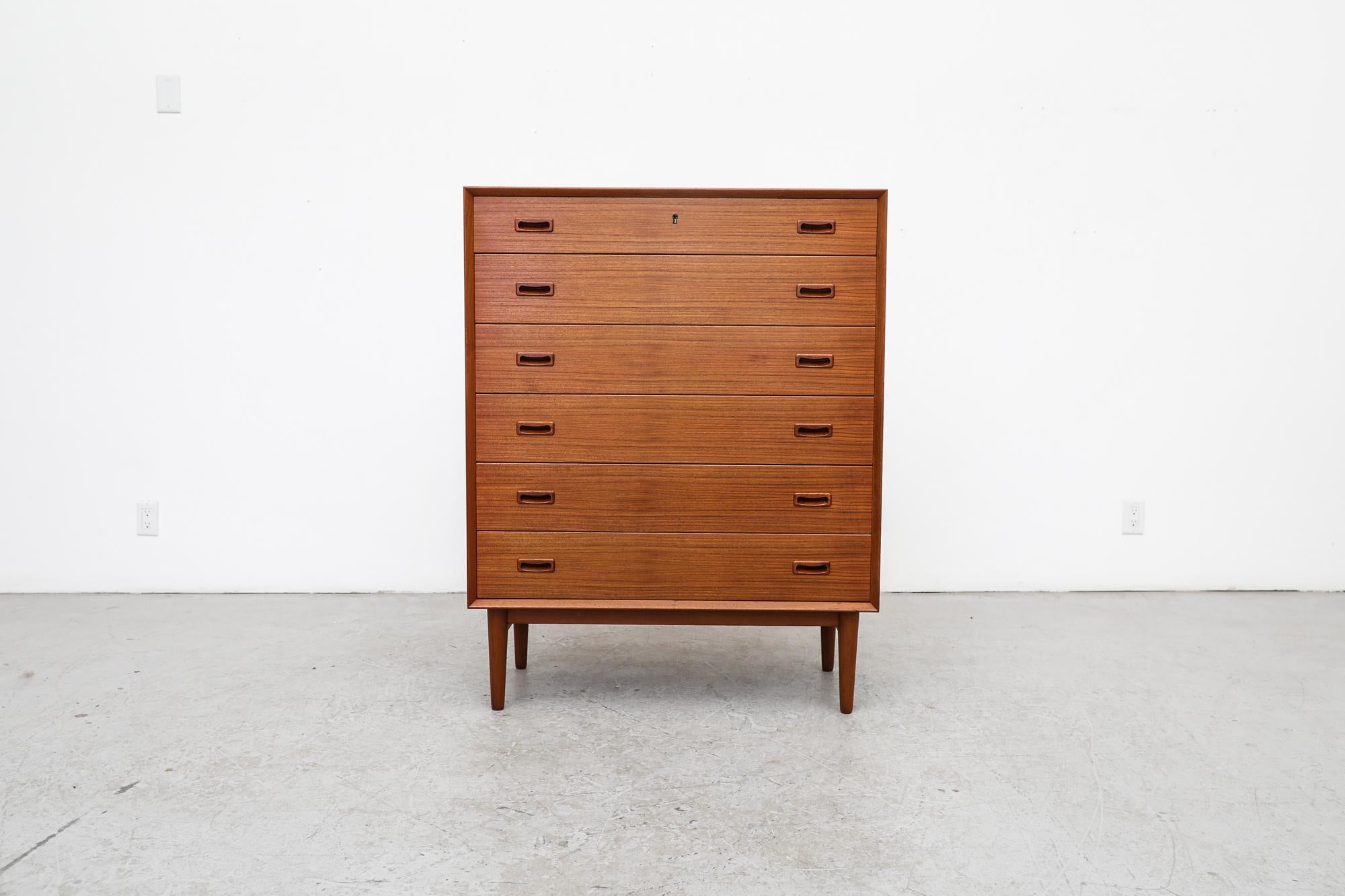 This mid-century Danish teak highboy from France & Søn has 6 drawers, organic carved inset drawer pulls and tapered legs. There is a lock, yet no working key. It has been lightly refinished with some remaining wear, consistent with its age and use.