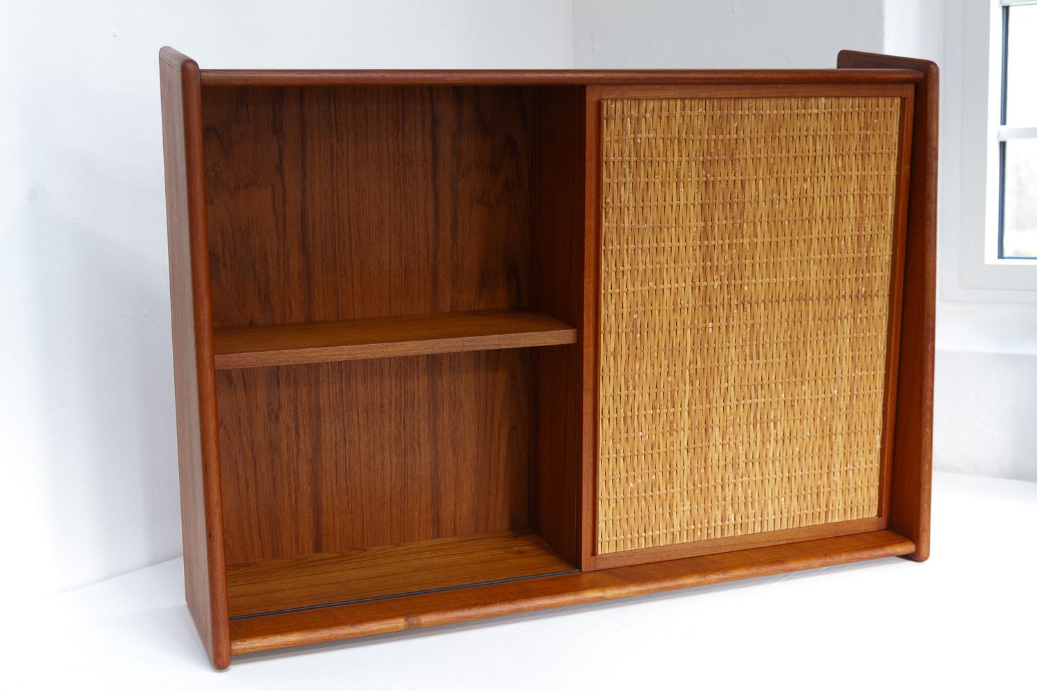Dänischer Wandwaschtisch aus Teak und Rohr mit Spiegel, 1960er Jahre.

Eleganter skandinavischer Mid-Century Modern-Schrank mit einer Schiebetür aus Teakholz mit Rattangeflecht. Eine Seite mit Regal und die andere mit Spiegel und Lampe.
Geeignet für
