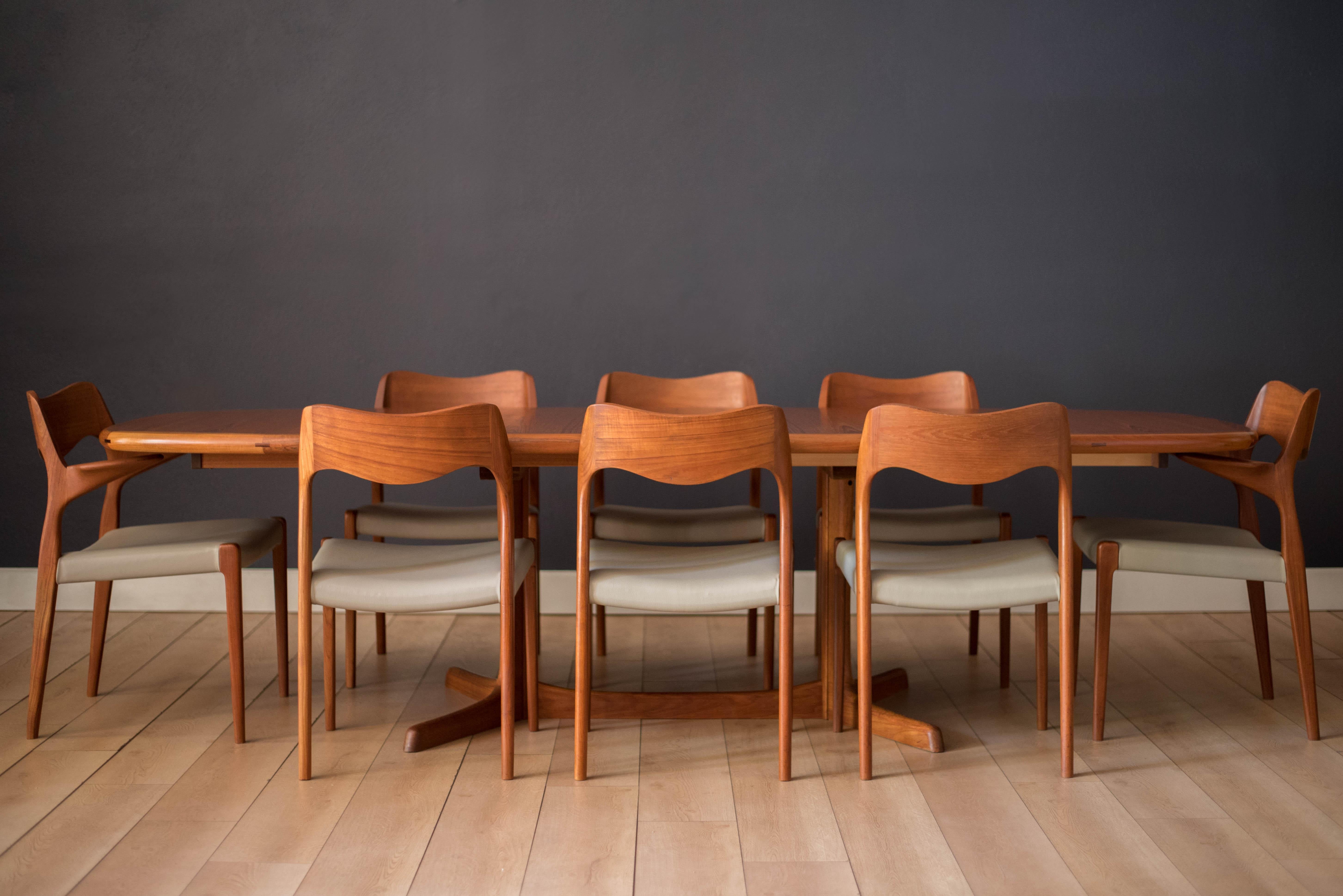 Mid-Century Modern round oval dining table in teak with rosewood accents by Rasmus. This piece features a convenient double pedestal style base that allow chairs to easily tuck in and seat up to 10 guests comfortably. Includes two extendable leaves