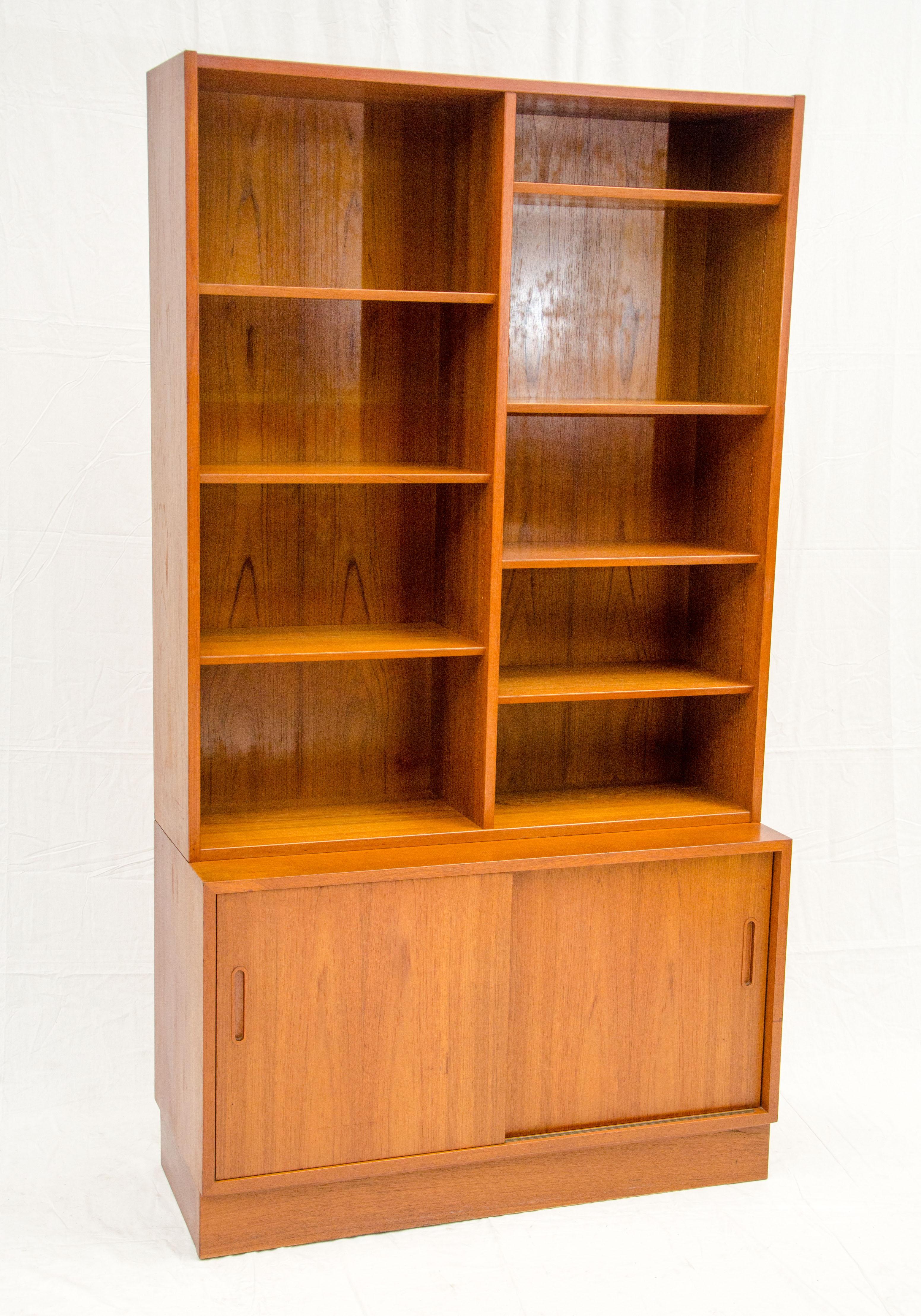 This very nice Danish teak bookcase has a storage cabinet under the shelving section. The storage cabinet has two sliding doors and a beech interior. There are three adjustable shelves as well as a small drawer that slides out. The storage base