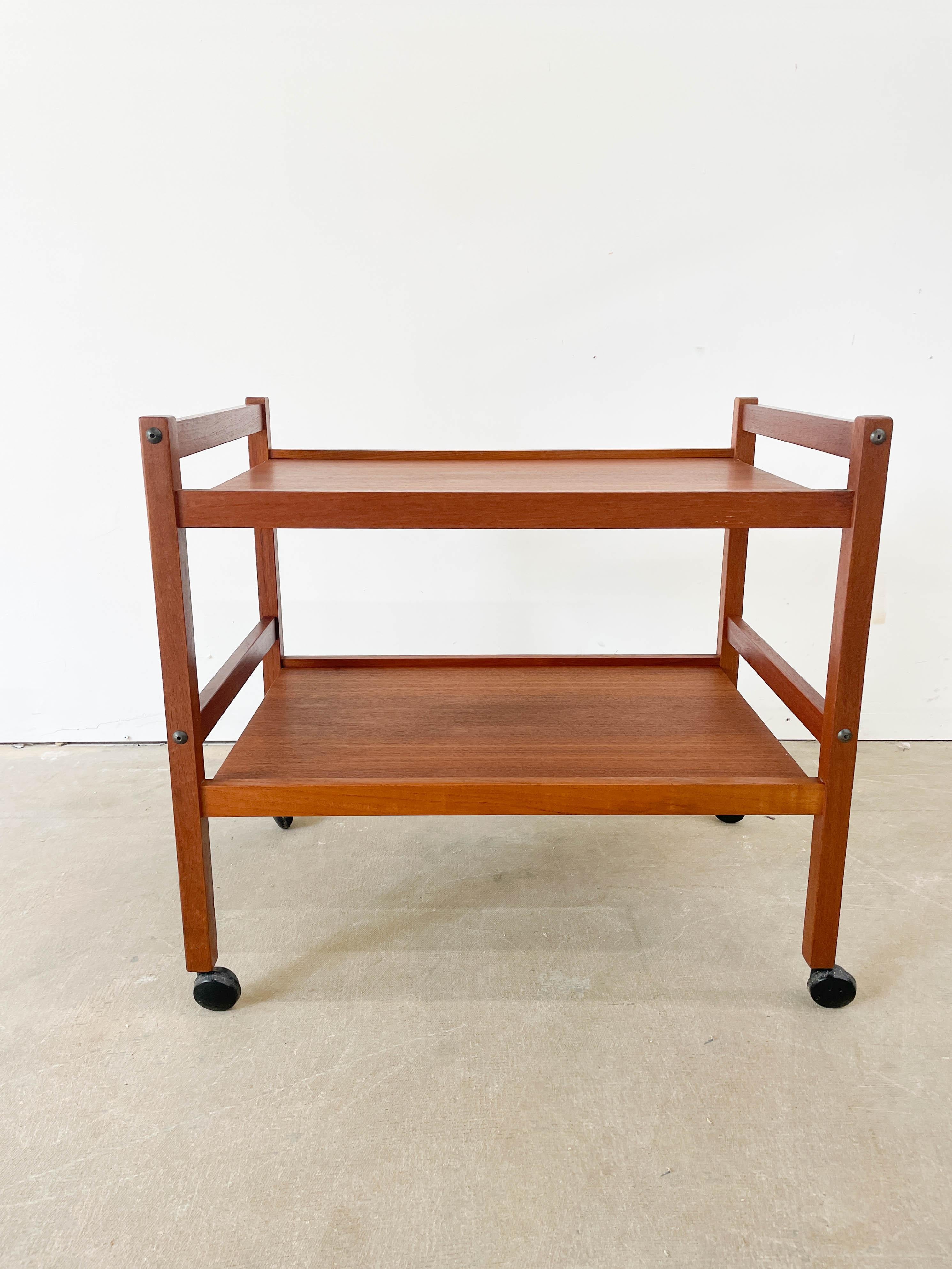 Minimalist Danish Modern teak tea or bar cart made in Denmark by Spottrup. Perfect for storing your teas, coffees, snacks, drinks or whatever else you fancy. Moves well with original casters and is very solidly built. Recently refinished, the teak