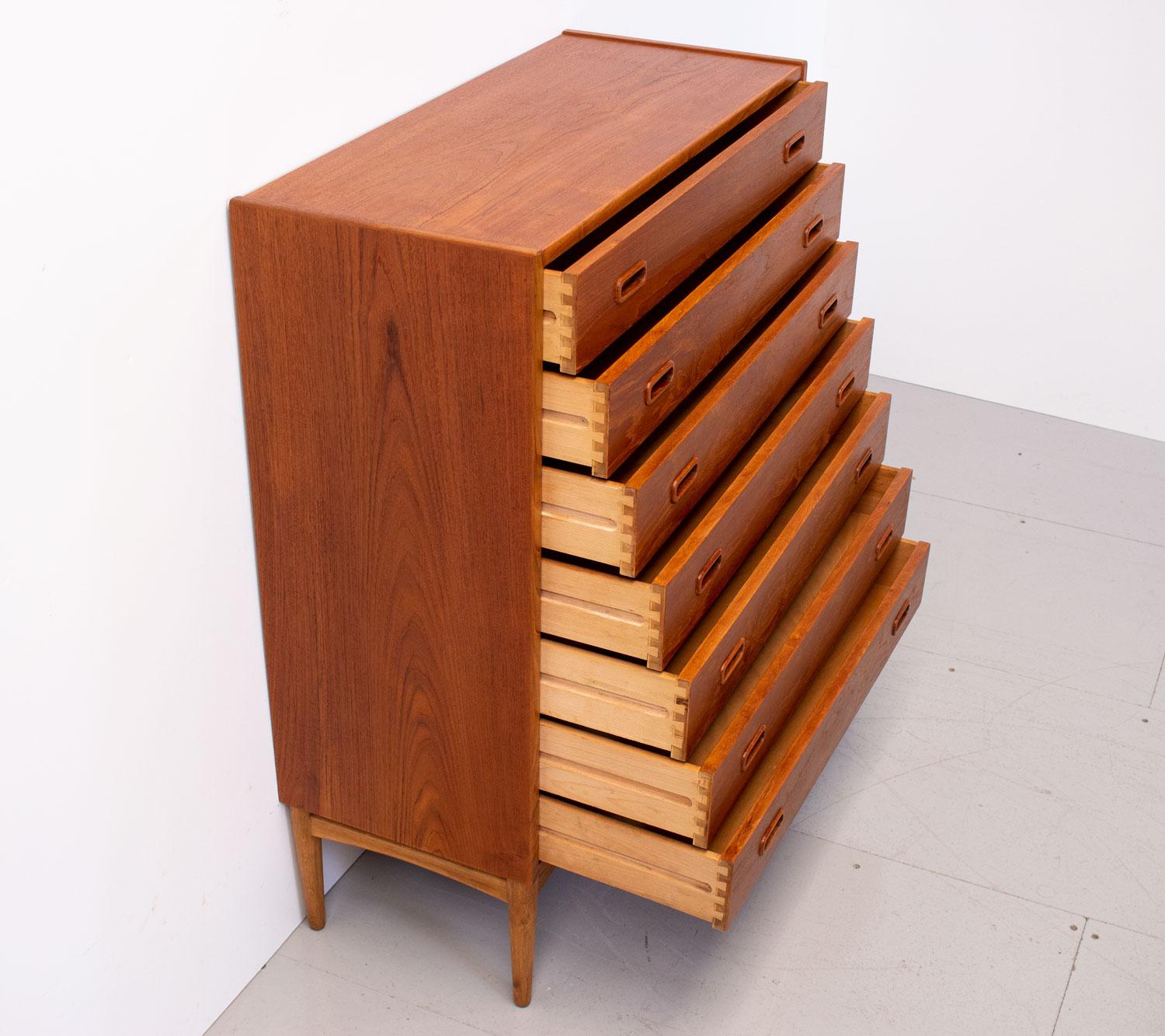 Stylish and minimalist Danish teak chest of drawers designed by Arne Hovmand-Olsen for Mogens Kold in the 1950s. It has 7 wide drawers with carved recessed handles and oak legs.