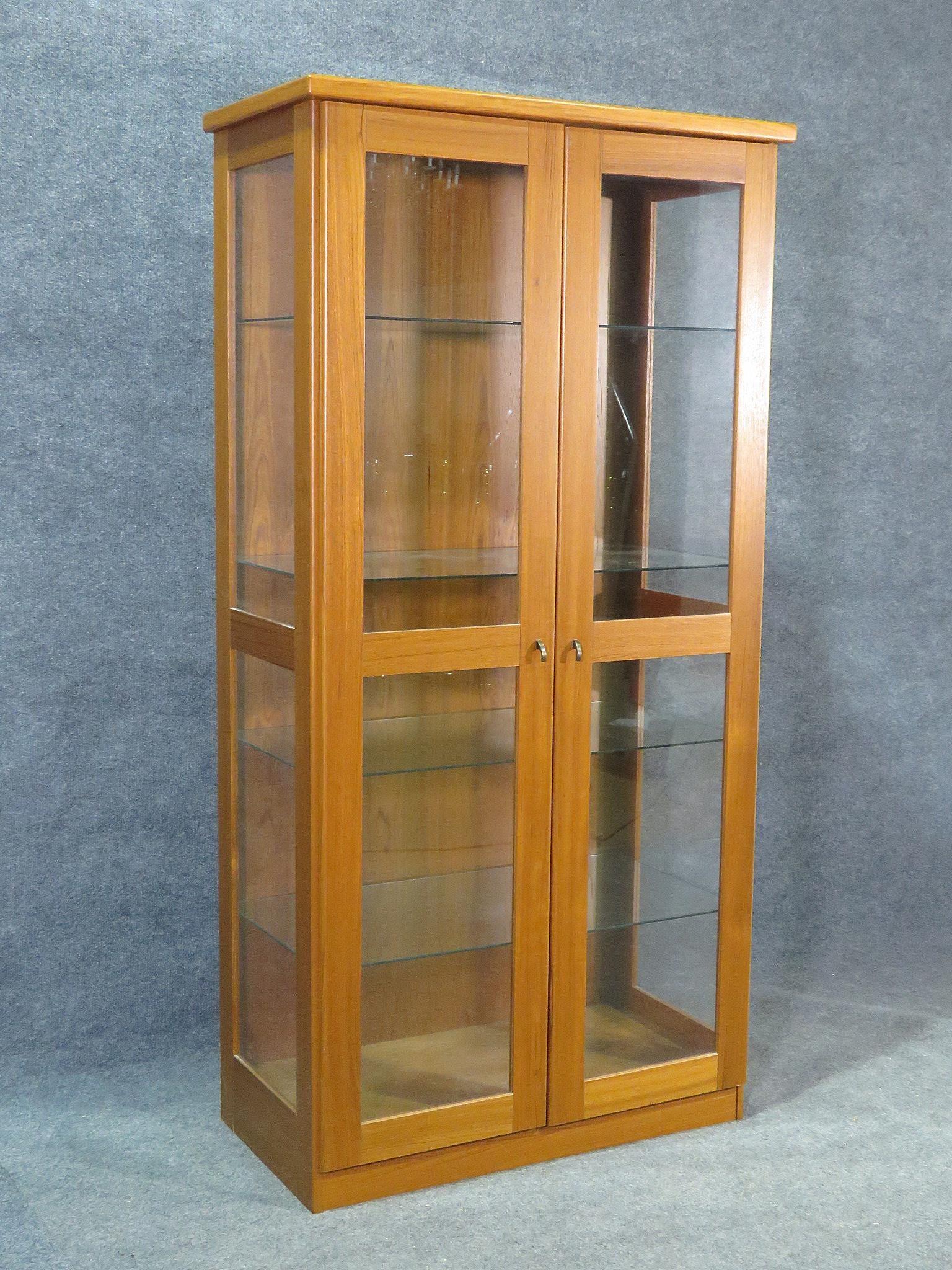 An elegant Mid-Century Modern cabinet with four glass shelves and interior lighting, this piece is perfect for displaying china or other decorative items. Please confirm item location with seller (NY/NJ).