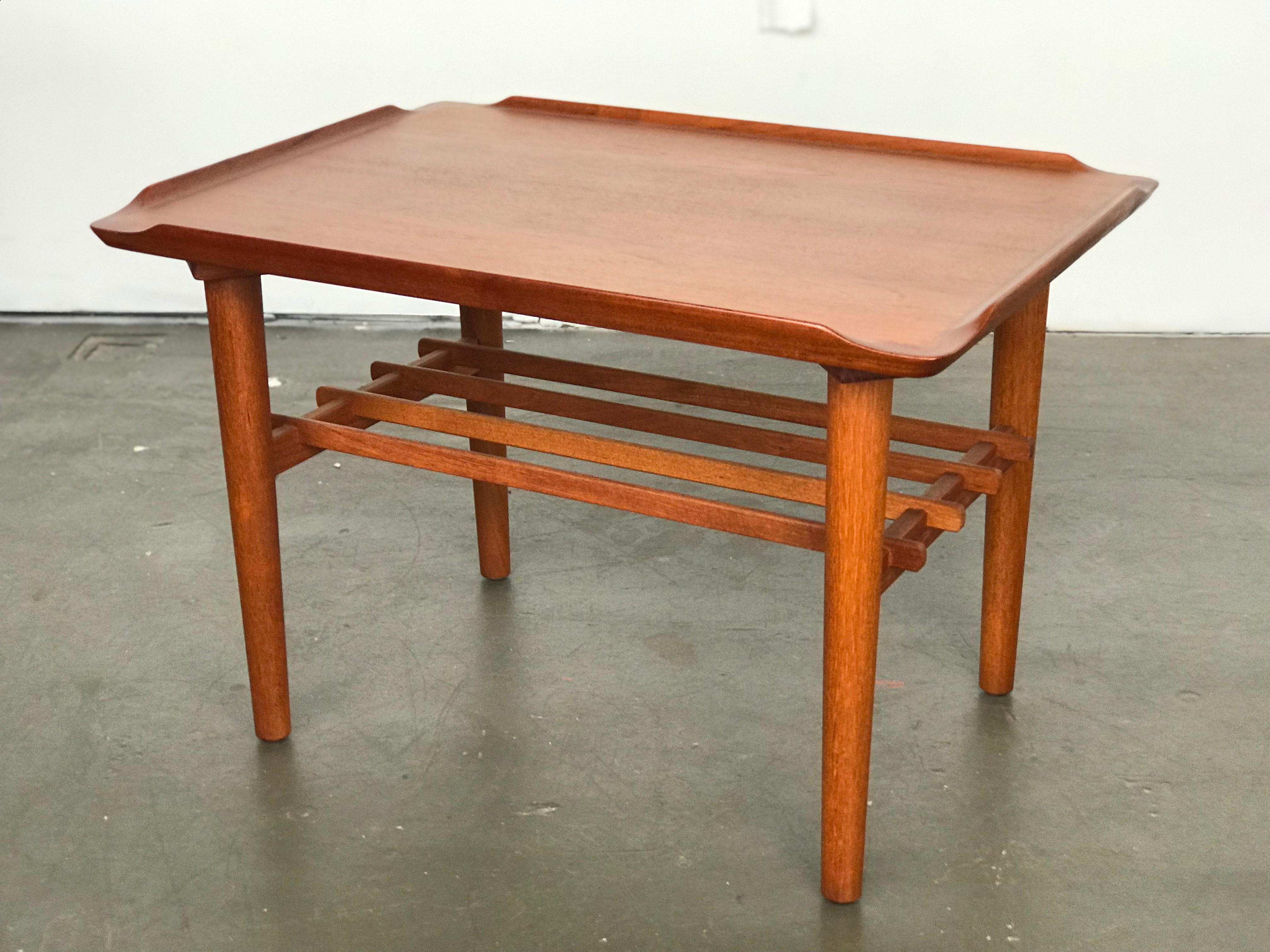 Excellent teak side or petite coffee table by Georg Jensen for Kubus. Lovely sculpted edges. Magazine rack is detachable. The legs unscrew - this is such a well made piece. 
This can be shipped parcel post since the legs unscrew the and rack is