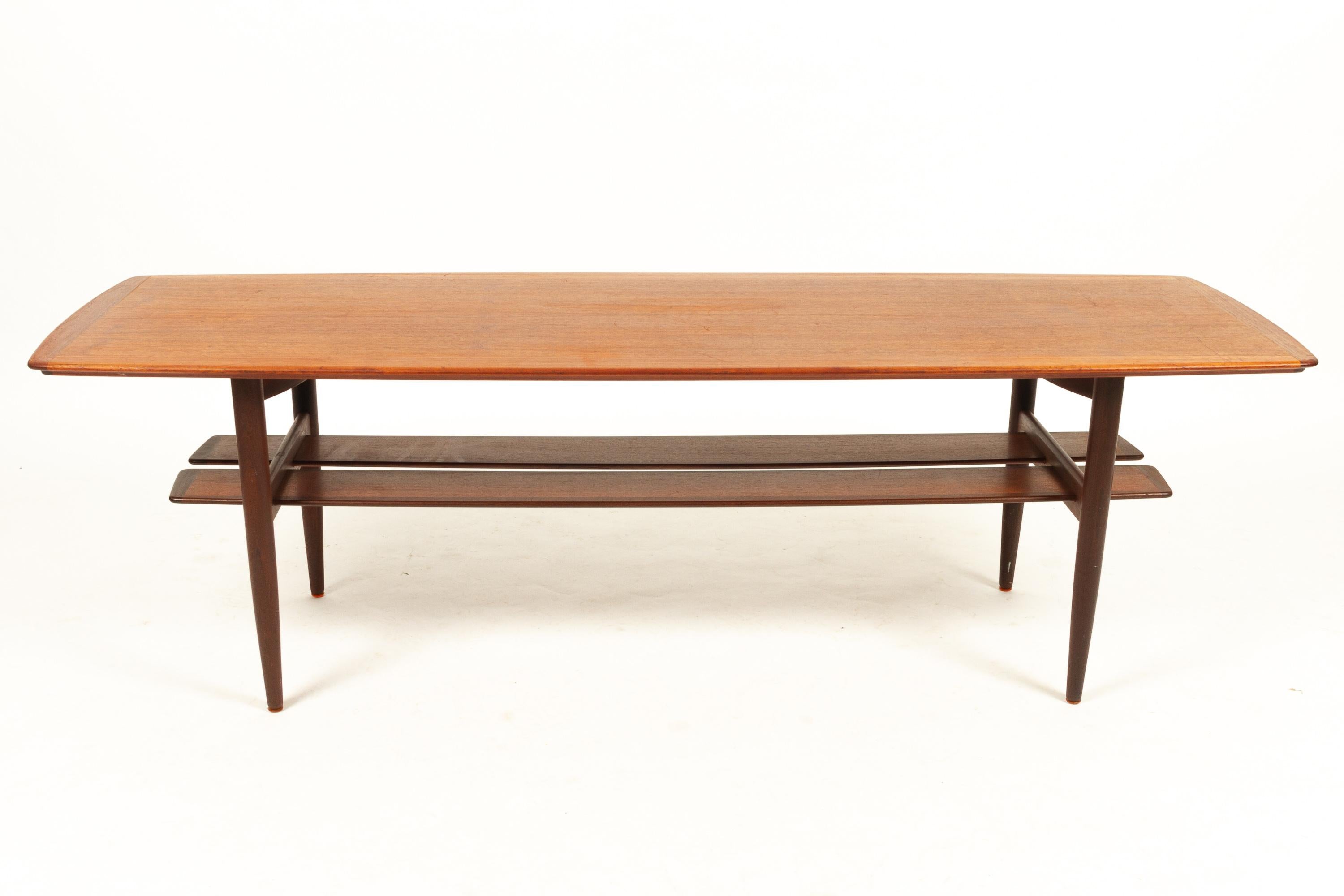Danish teak coffee table by H. W. Klein for Bramin 1960s.
Designed in 1962. Beautiful Mid-Century Modern boat/surfboard shaped coffee table with split magazine shelf. Top and shelves are framed in solid teak. Lovely teak veneer on top and shelves.