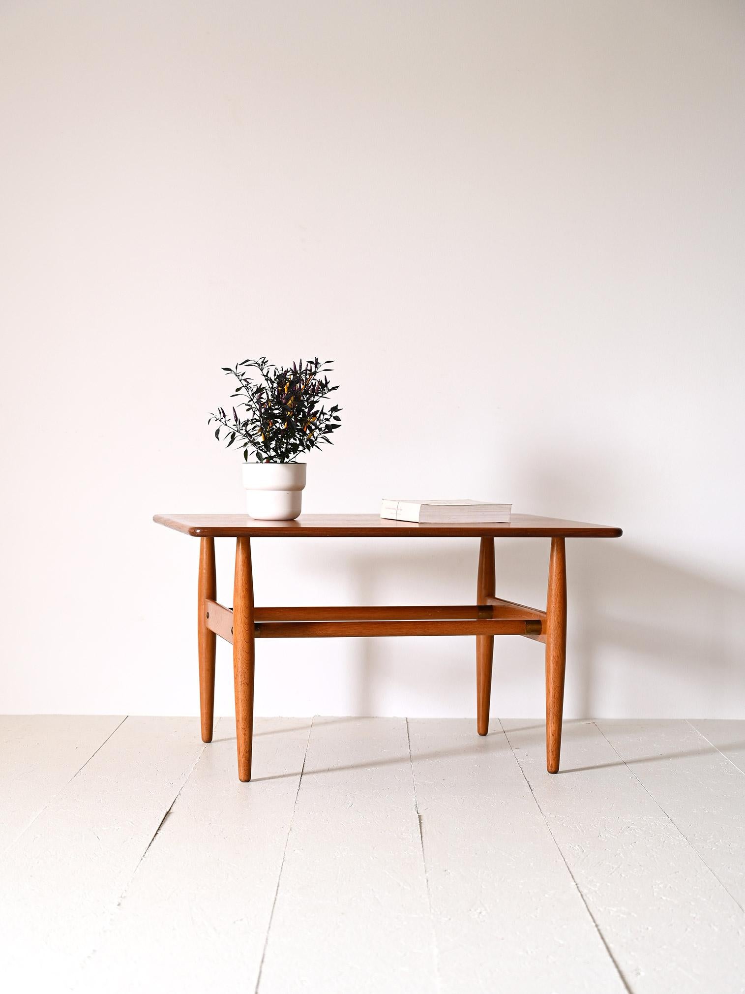 Vintage 1960s rectangular coffee table.

An original Scandinavian piece of furniture with soft, minimal lines. Consisting of the top with rounded corners and conical legs as well as the two central bars that serve as magazine racks.
The warm shade