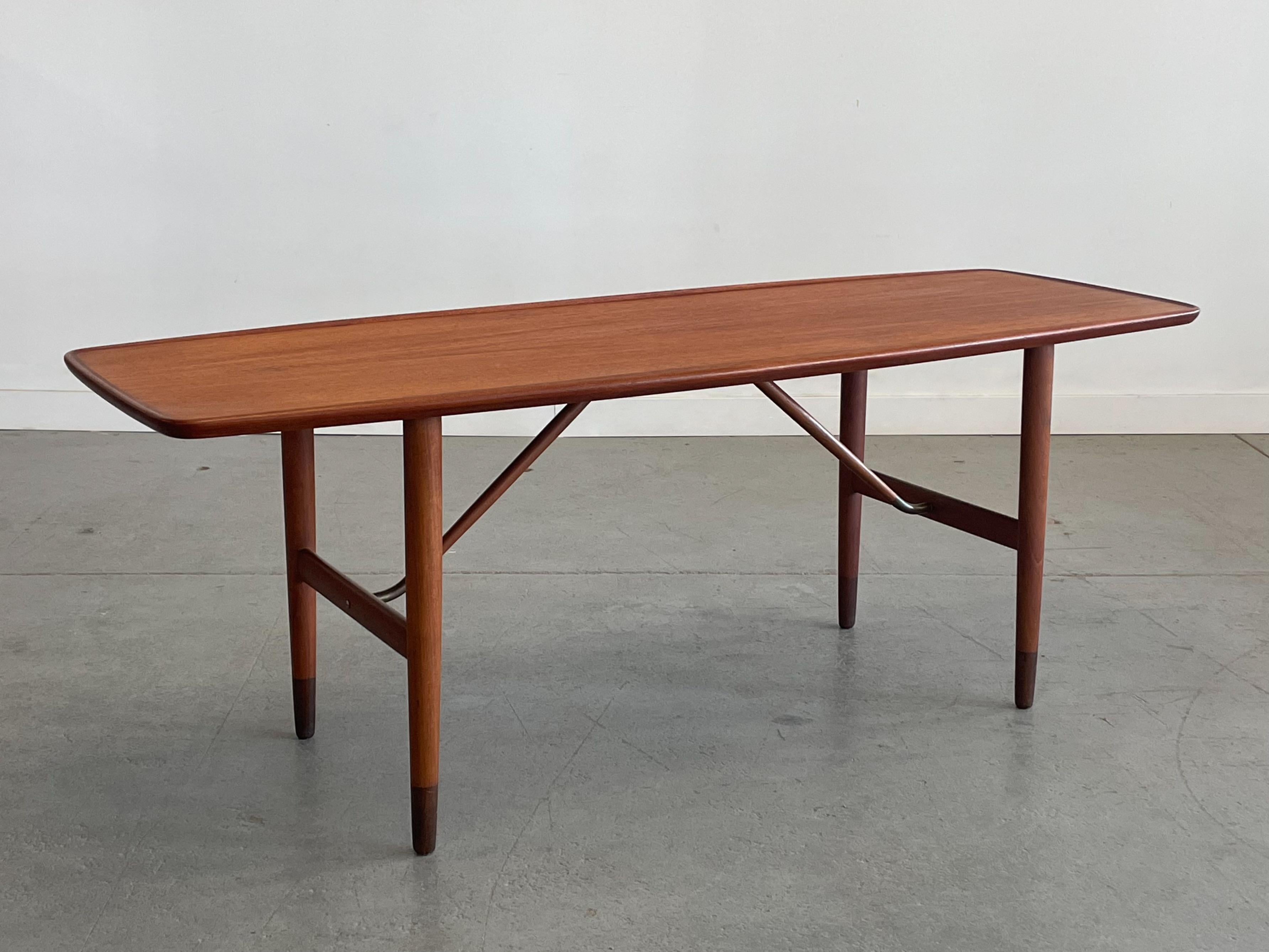 Une table basse / table de canapé en teck danois absolument superbe, avec des détails bien pensés aux bons endroits. Cette pièce présente un bord supérieur sculpté, un châssis angulaire avec des détails en laiton et des pieds coniques en afrormosia.