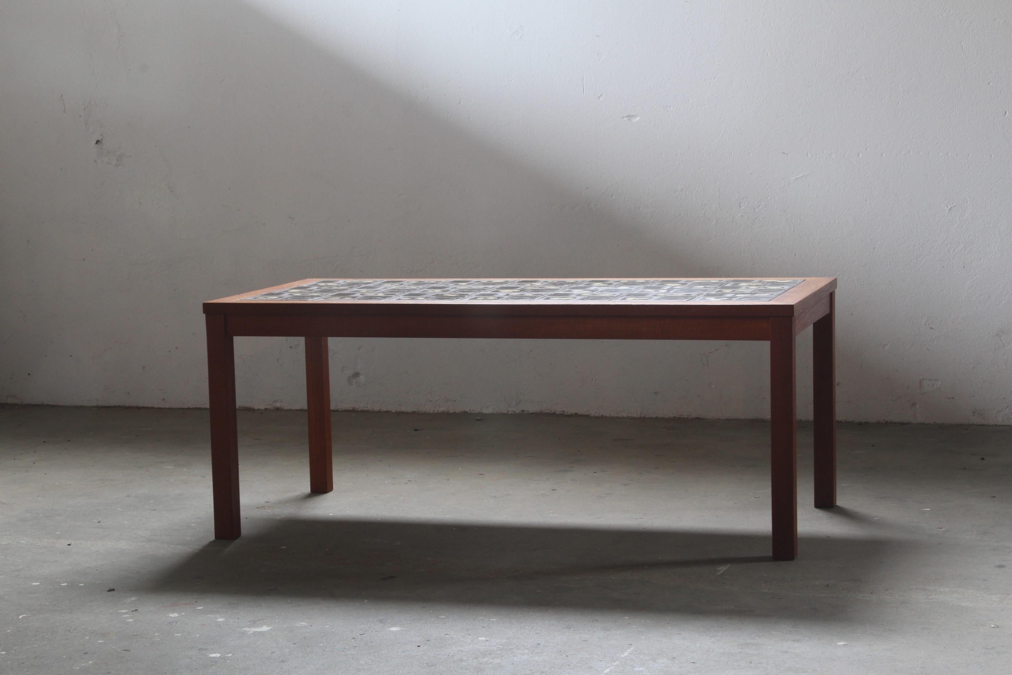 This Danish teak coffee table, adorned with exquisite ceramic tiles, is an ideal addition for post-dinner gatherings. The handmade artistic patterns seamlessly blend teak wood and ceramics. In excellent condition, it shows minimal signs of use,