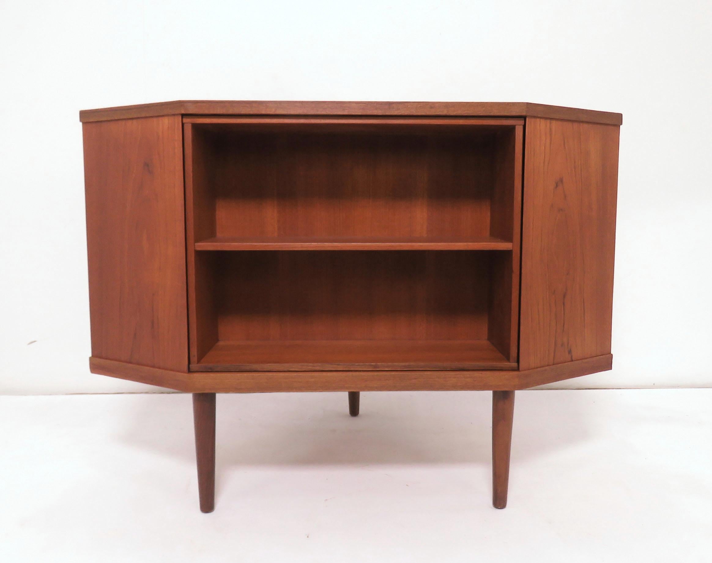 Teak corner cabinet with revolving bookcase, revealing storage for five liquor bottles and stemware, with mirrored back, circa 1960s. In the manner of designs by Torbjorn Afdal of Norway. Would make a wonderful media stand for a flat screen in urban