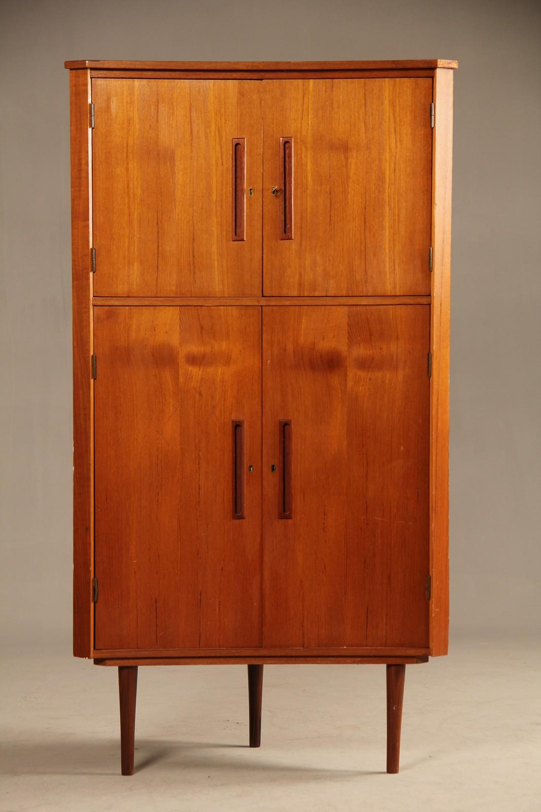 Danish Mid-Century Modern corner cabinet of finished teak wood with doors which open to reveal shelves. Key included.
