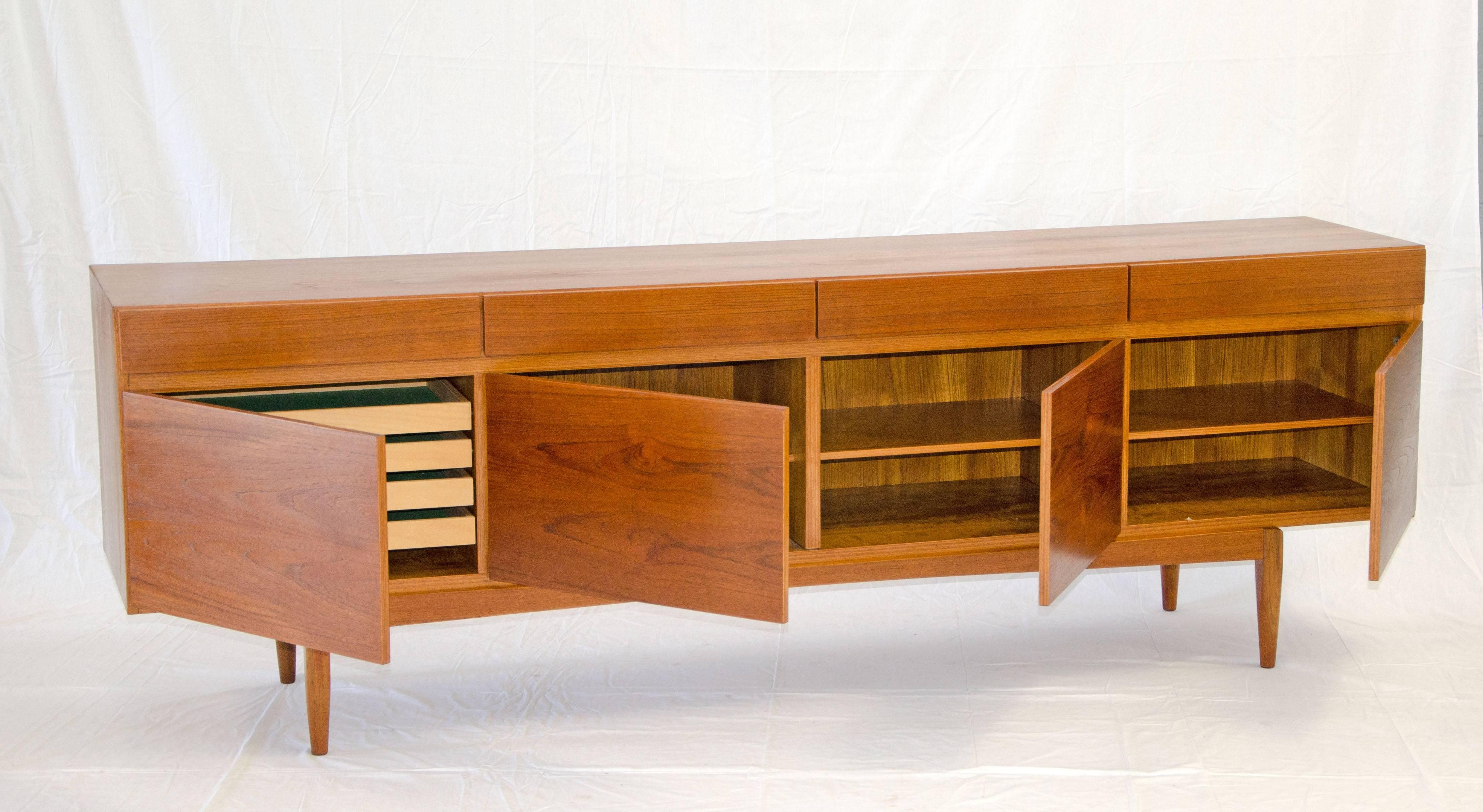 Extra long Danish teak credenza designed by Ib Kofod-Larsen with four storage drawers above four storage compartments. Three compartments have adjustable shelves and the fourth has four shallow pull out drawers for silverware or other uses. The four