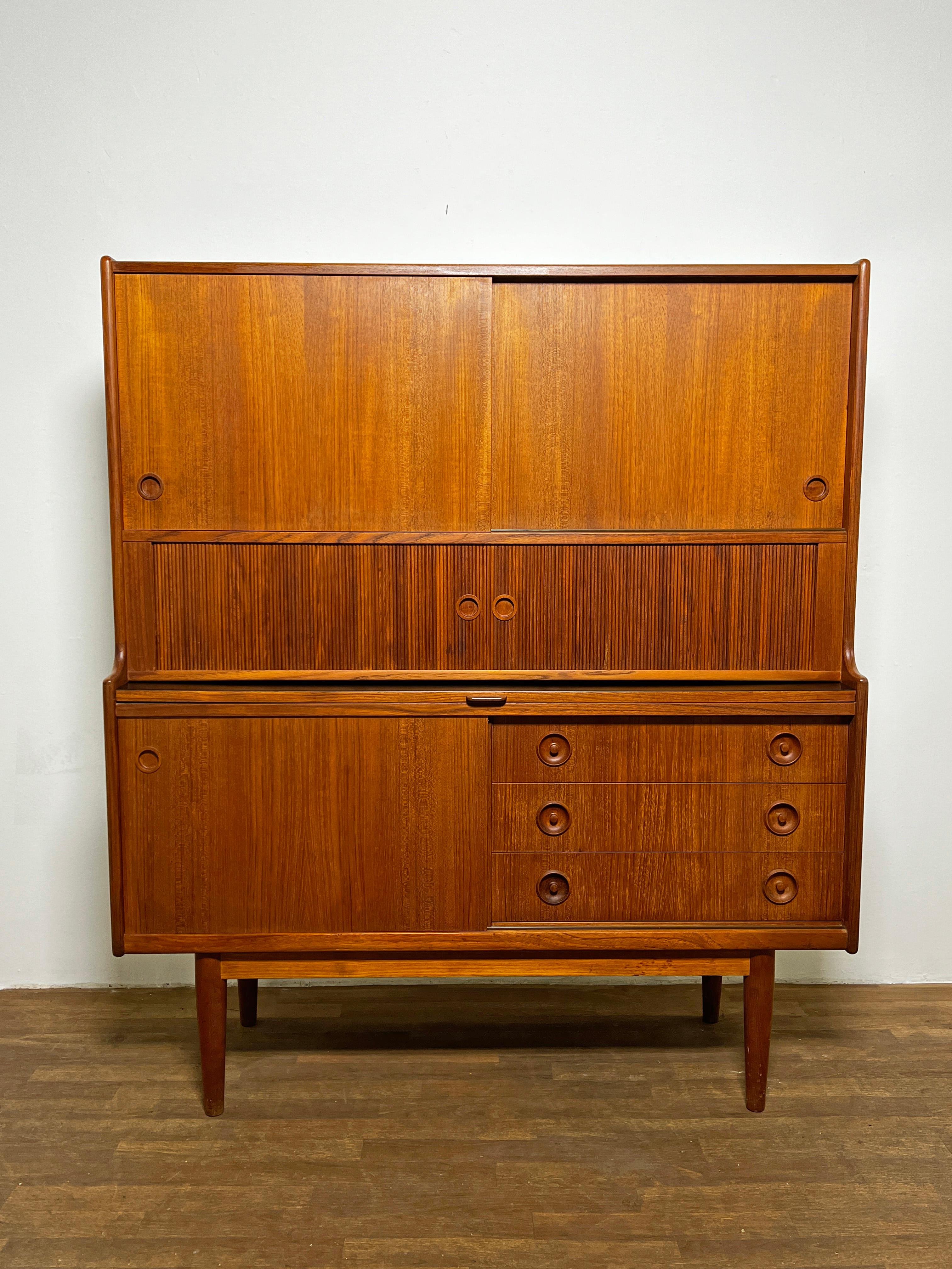 A 1960s Danish teak high sideboard with retractable serving shelf, shallow flatware drawers and ample storage. This is most often attributed to Johannes Andersen for J. Skaaning and Son, and alternatively to Bornholms. A classic Scandinavian storage