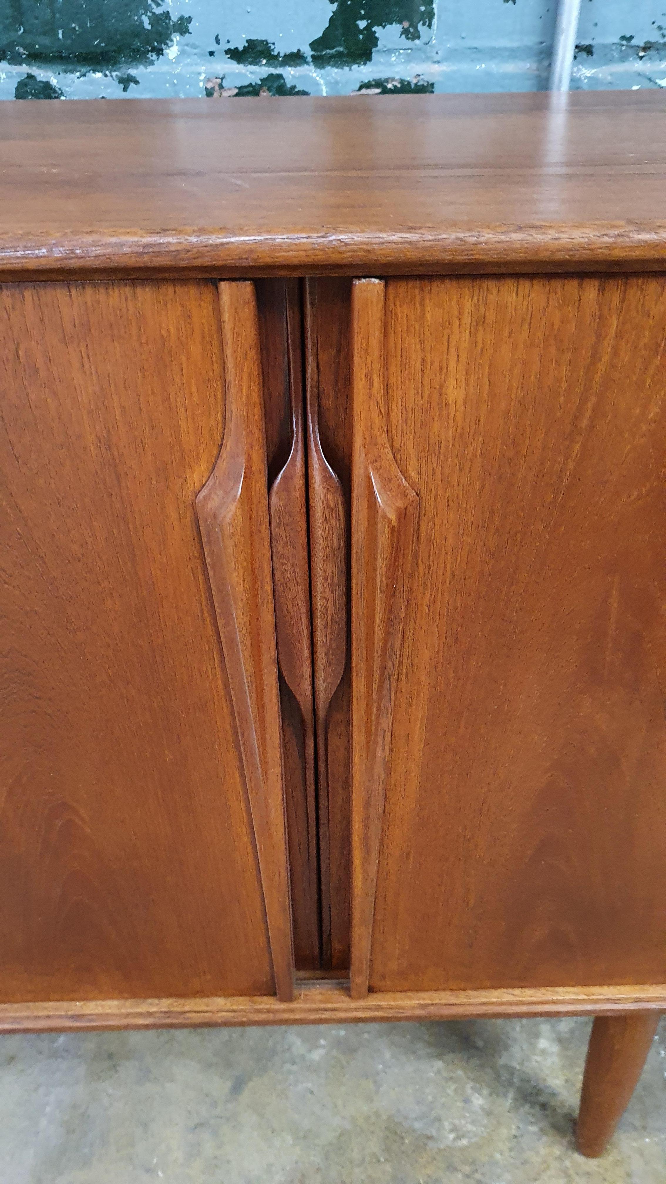 Beautiful teak credenza by Axel Christiansen for ACO mobler. Features 4 sliding doors with sculpted pulls. this aging piece has been completely refinished and is ready for another 70+ years.