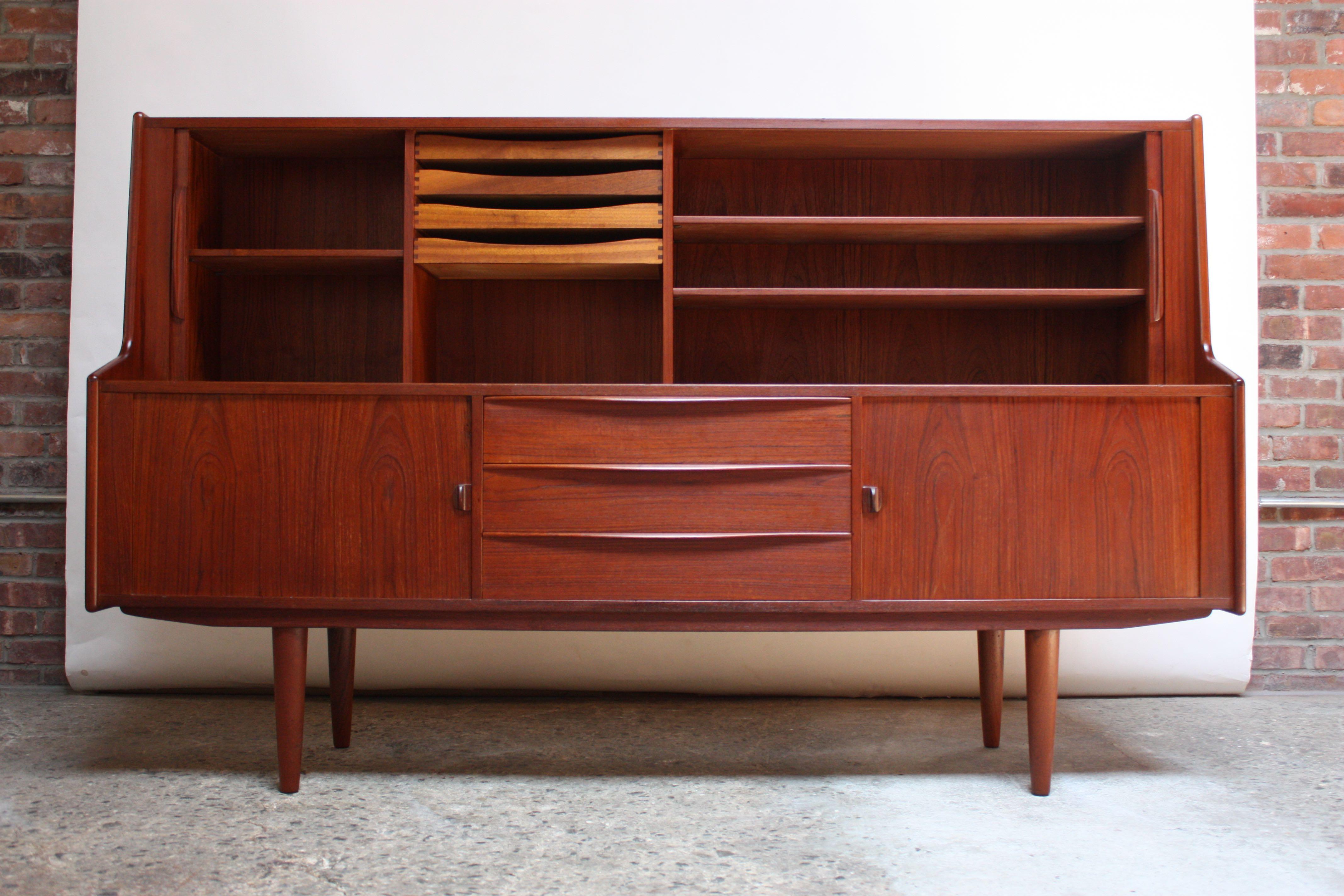IB Kofod-Larsen highboard designed for Faarup. Early example (1950s) in dark teak with multiple storage compartments. Narrow profile and relatively diminutive size for its design / storage capability. Top two tambour doors open to reveal two