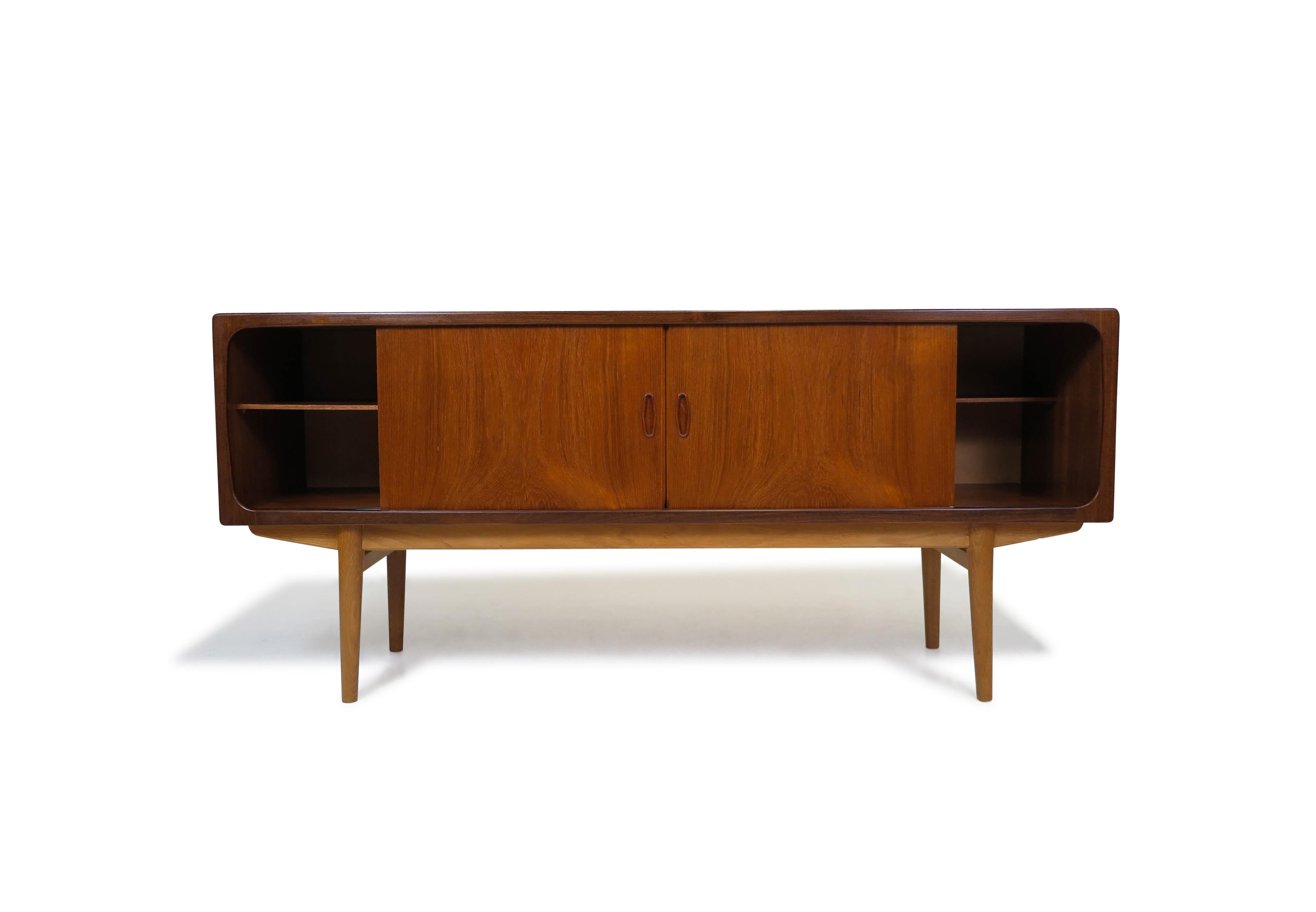 Mid-century teak credenza attributed to Johansen Andersen for Clausen Sons, Denmark, 1960s. This handcrafted sideboard is made from book-matched old-growth teak and features four sliding cabinet doors with carved recessed pulls. Opening the doors