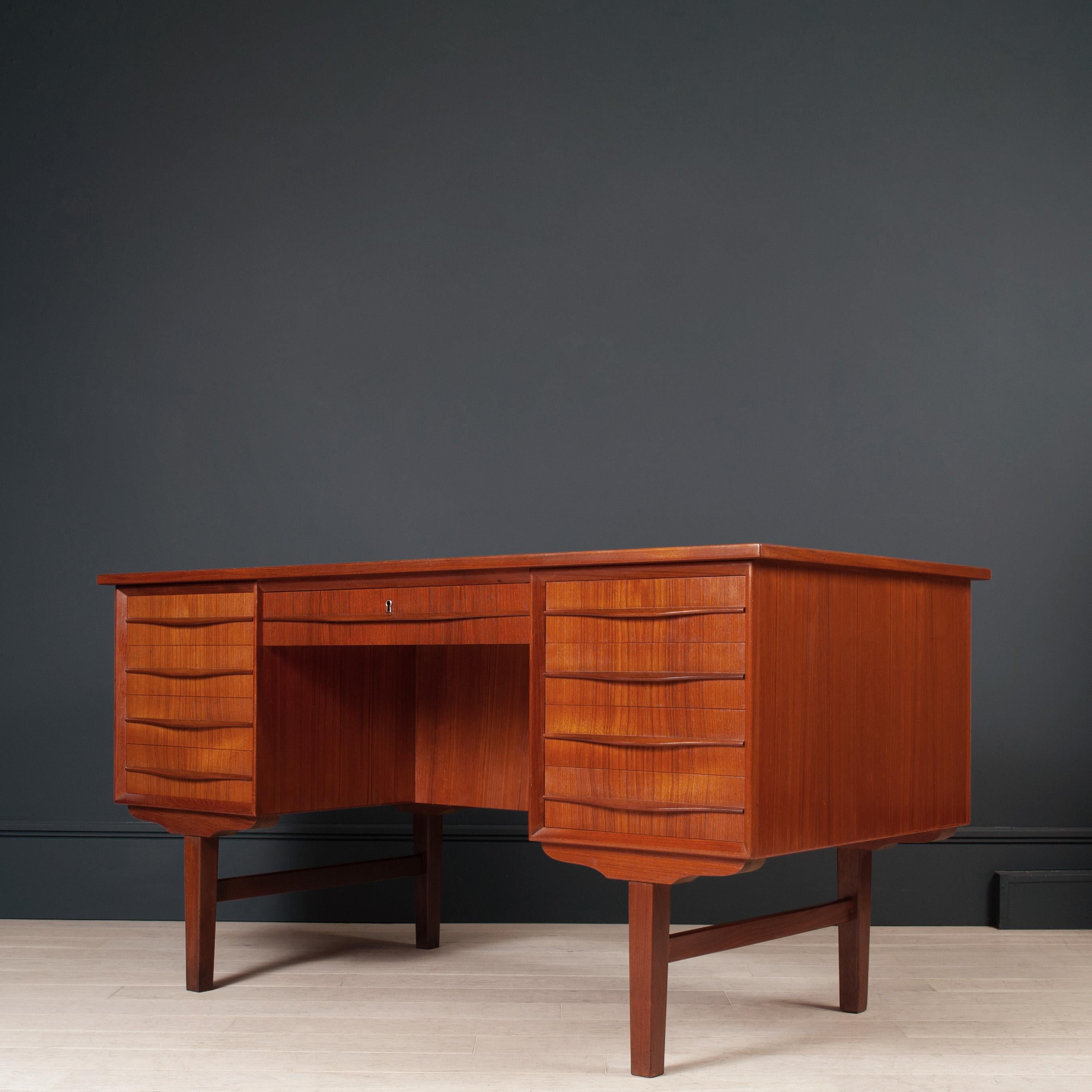 A substantial double bank drawer desk. Produced in Denmark circa 1960. Classical midcentury Scandinavian design. Rear section has 2 compartments and a double sliding door section housing one inner shelf. The top surface has been refinished in 
