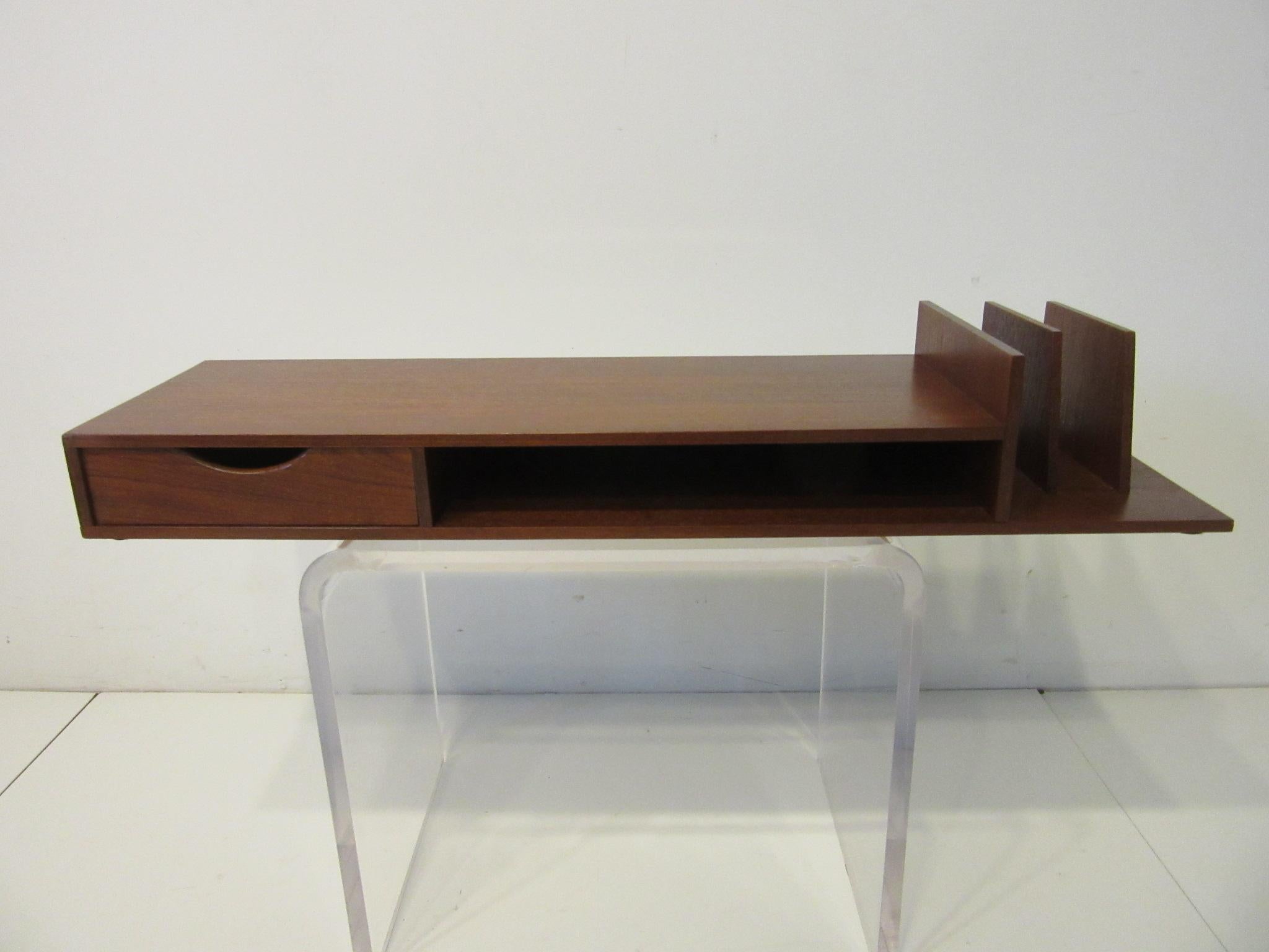 A nice accompaniment to your Danish desk this well crafted desk organizer has a small drawer to one side a storage space and a standup slots for mail . This teakwood piece sits on the top back of your desk to keep important things at hand.
