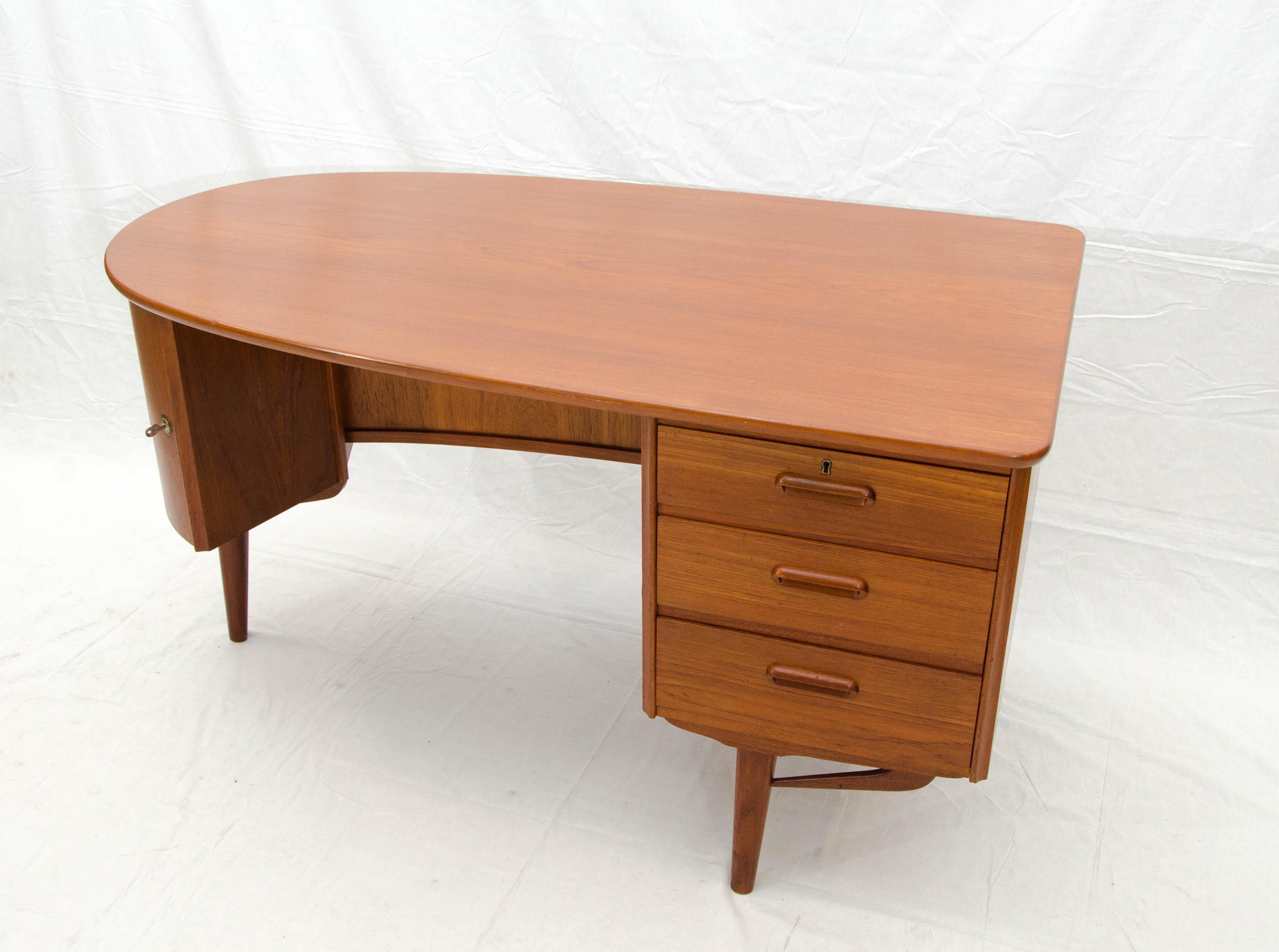 Very nice medium size Danish teak desk with an elliptical curve on one end. There are three storage drawers on one side, the interior drawer depths are 3 1/4
