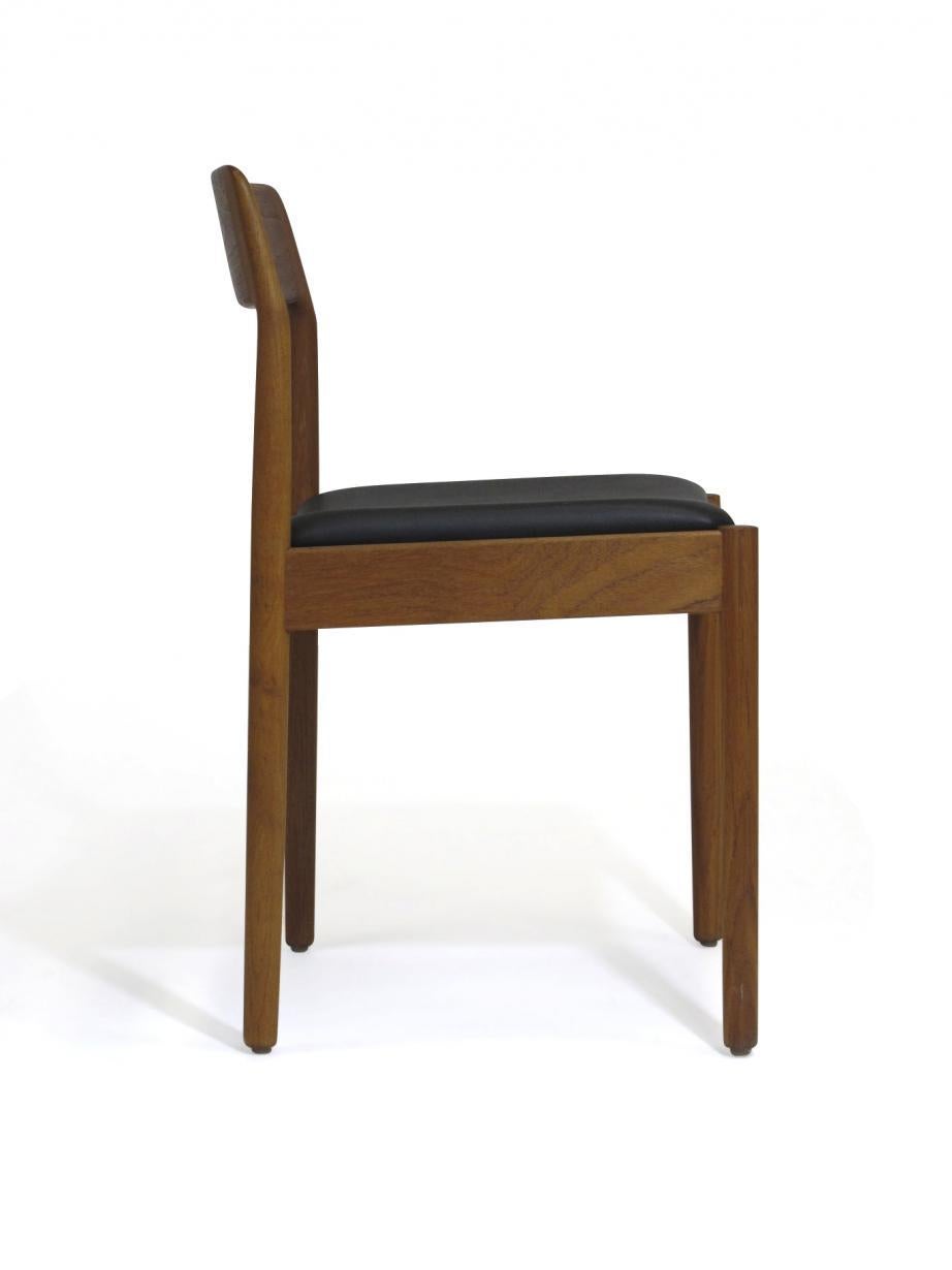 Four midcentury Danish dining chairs crafted of solid teak with newly upholstered seats in black vinyl.
 