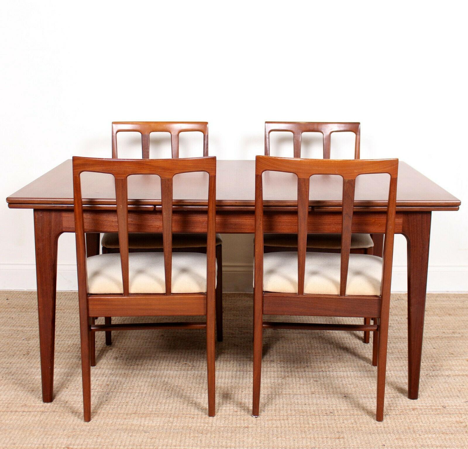 An impressive 20th century five-piece dining suite offered in very good condition.

Constructed from solid teak.

The dining table - extending by way of drawer leaf mechanism - raised on tapered legs. The chairs with the same angular tapered