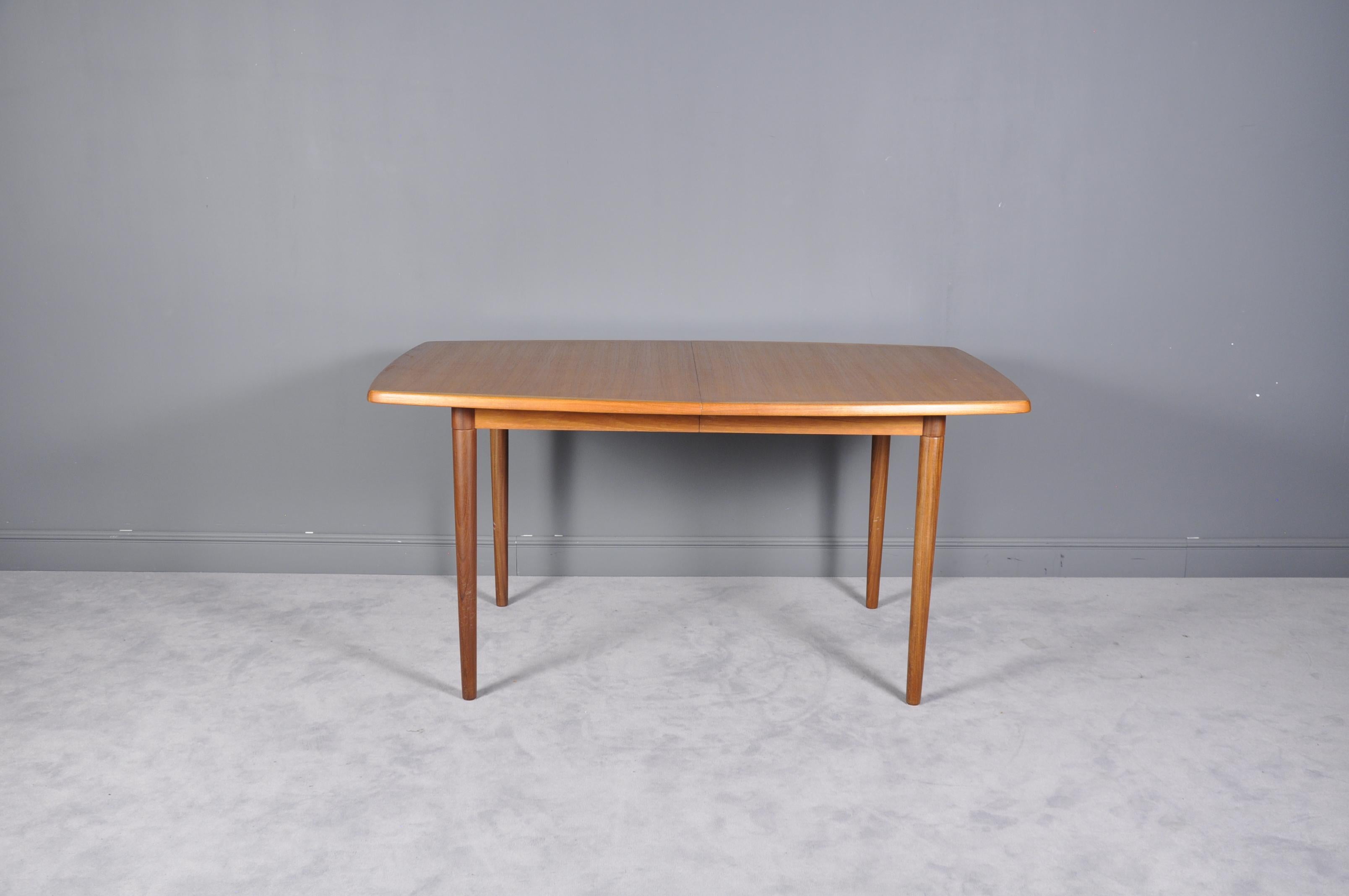 Scandinavian Modern teak wood dining table by Gustav Bahus, Norway. This expandable dining table by Gustav Bahus features beautiful teak wood grain curved rectangular top, unique joinery, tapered legs, and extends with two leaves. With both leaves