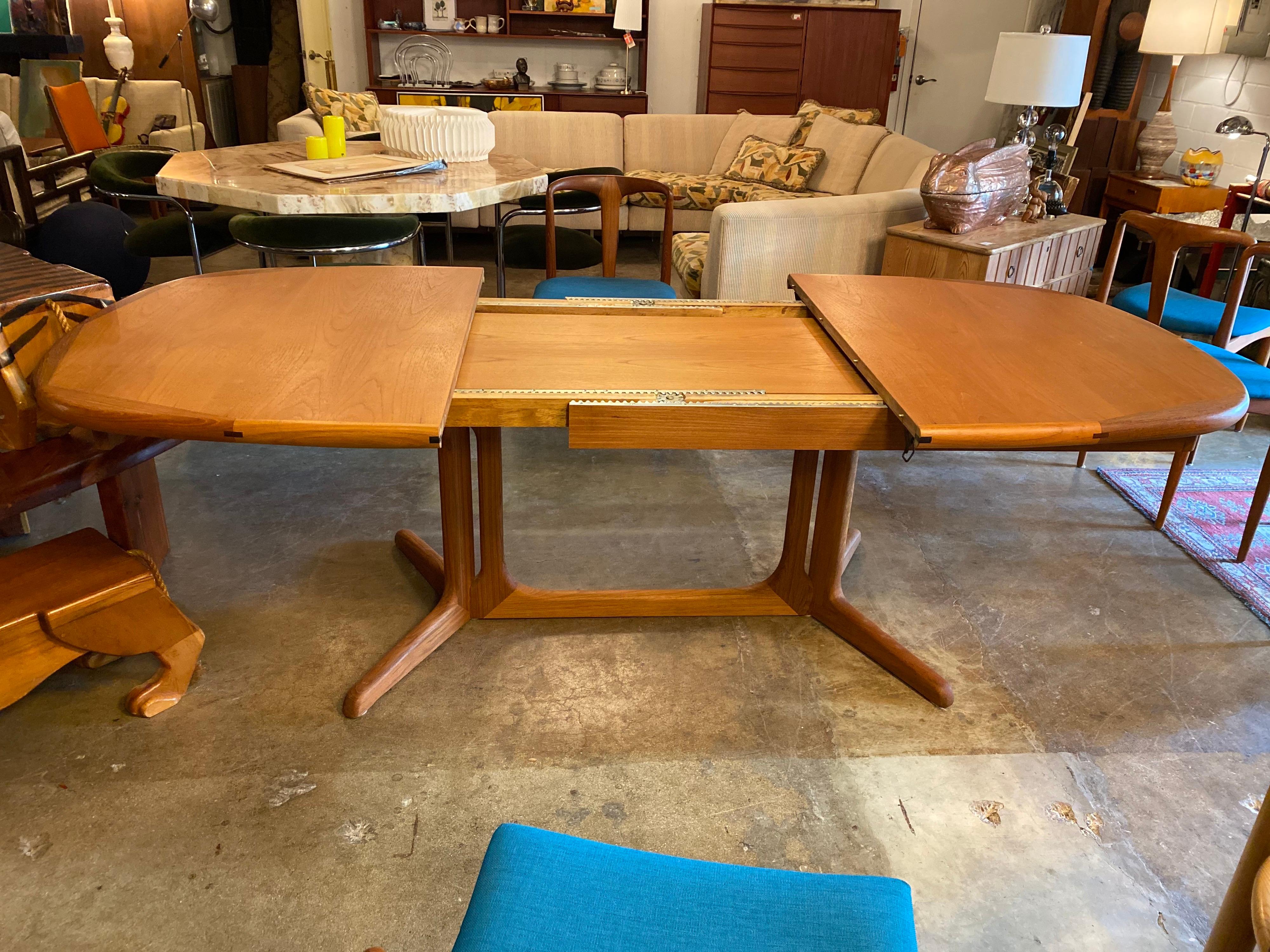 Mid-century Danish teak dining table with two leaves stored within, extending the entire table and extra 39 inches. This boat rounded rectangle teak table is beautiful and easily seats eight. Very good condition.