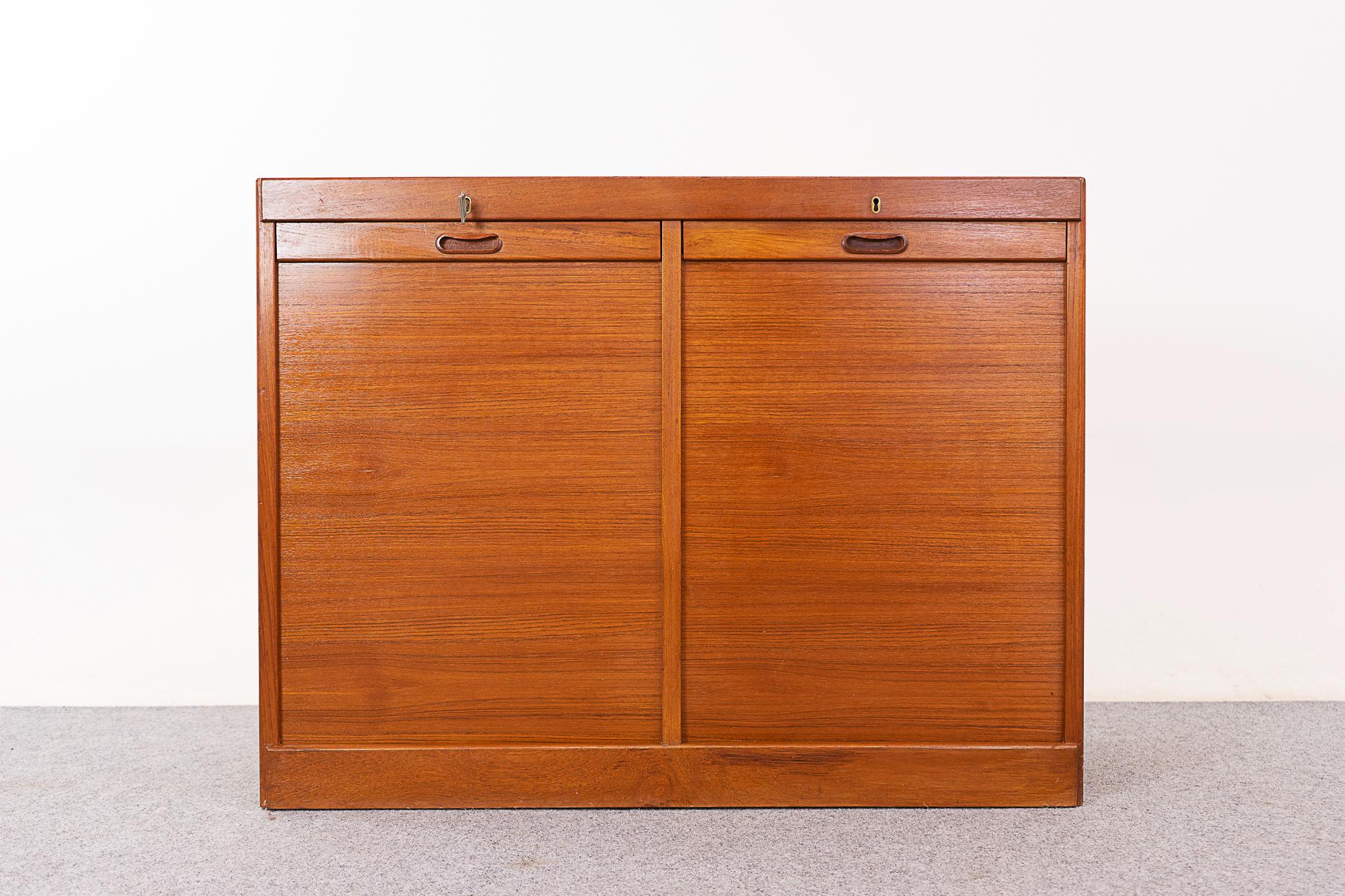 Teak Danish tambour door filing cabinet, circa 1960's. Compact double bank cabinet with locking tambour doors that magically disappear when opened. Interior drawers and file hanging system. Low enough to hang art above, or place a lovely Danish