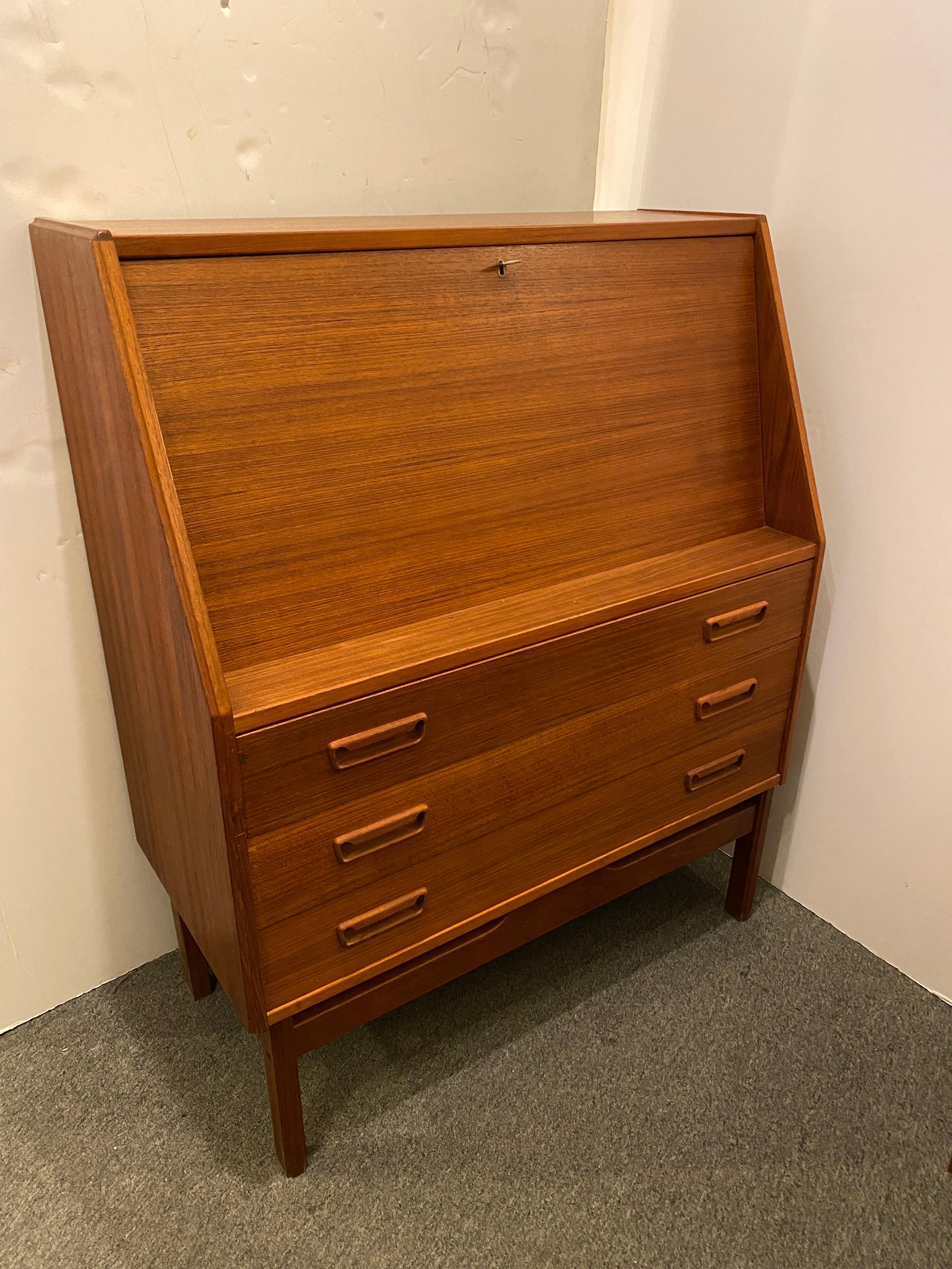 Dyrlund Teak Drop Front Desk with 3 pull out lower drawers.  Very clean condition.  Key acts as knob but does not lock fold down.  2 little pullout drawers inside desk area.  Top of desk was refinished.
