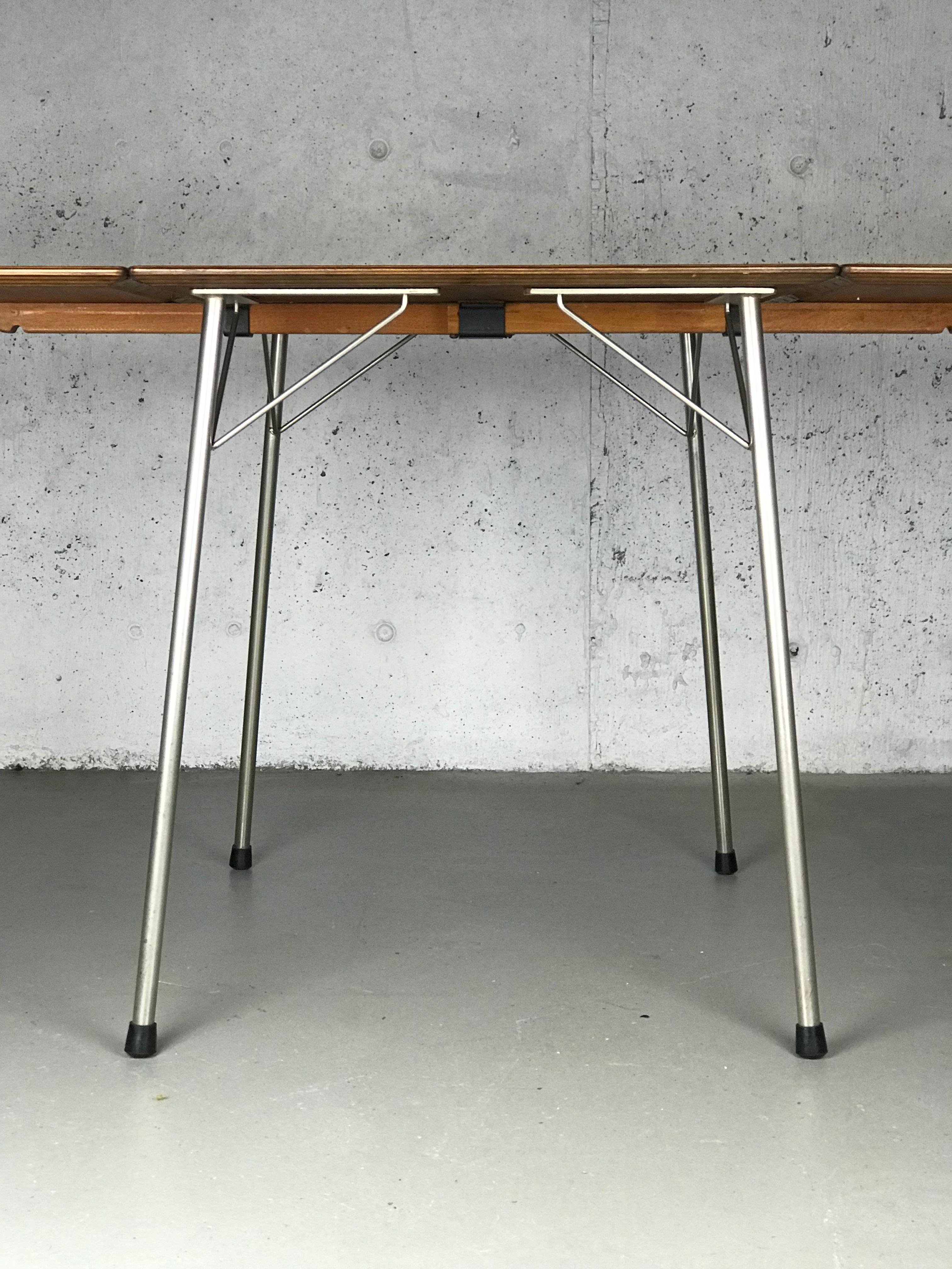 Minimalist drop-leaf dining table in teak and steel designed by Arne Jacobsen for Fritz Hansen, 1950s. The top has been refinished using Danish oil. The steel legs have been cleaned and yet show minor wear. 

With the leaves down the table is: