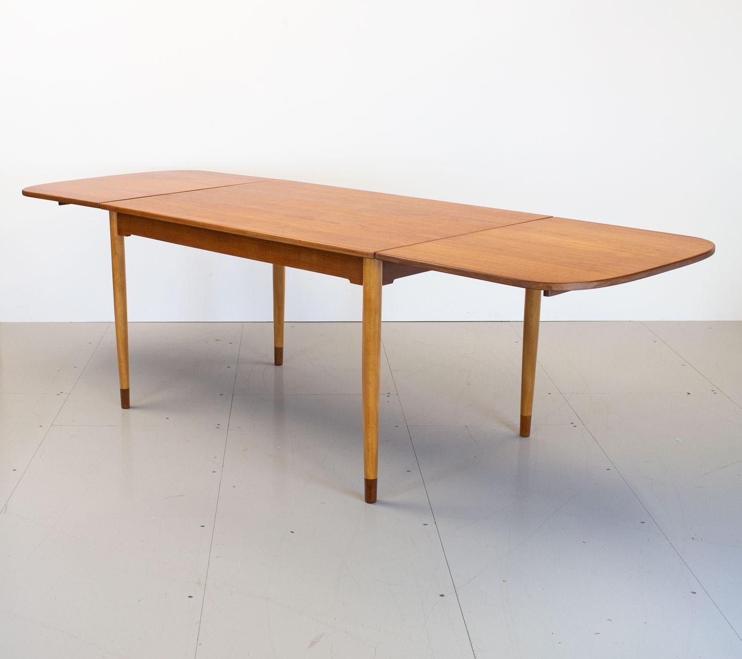 1950s Danish teak drop leaf dining table designed by Børge Mogensen for Søborg Møbelfabrik. This practical dining table can seat 4 people when closed and up to 10 people when fully extended by the drop down leaves that are held in place with pull