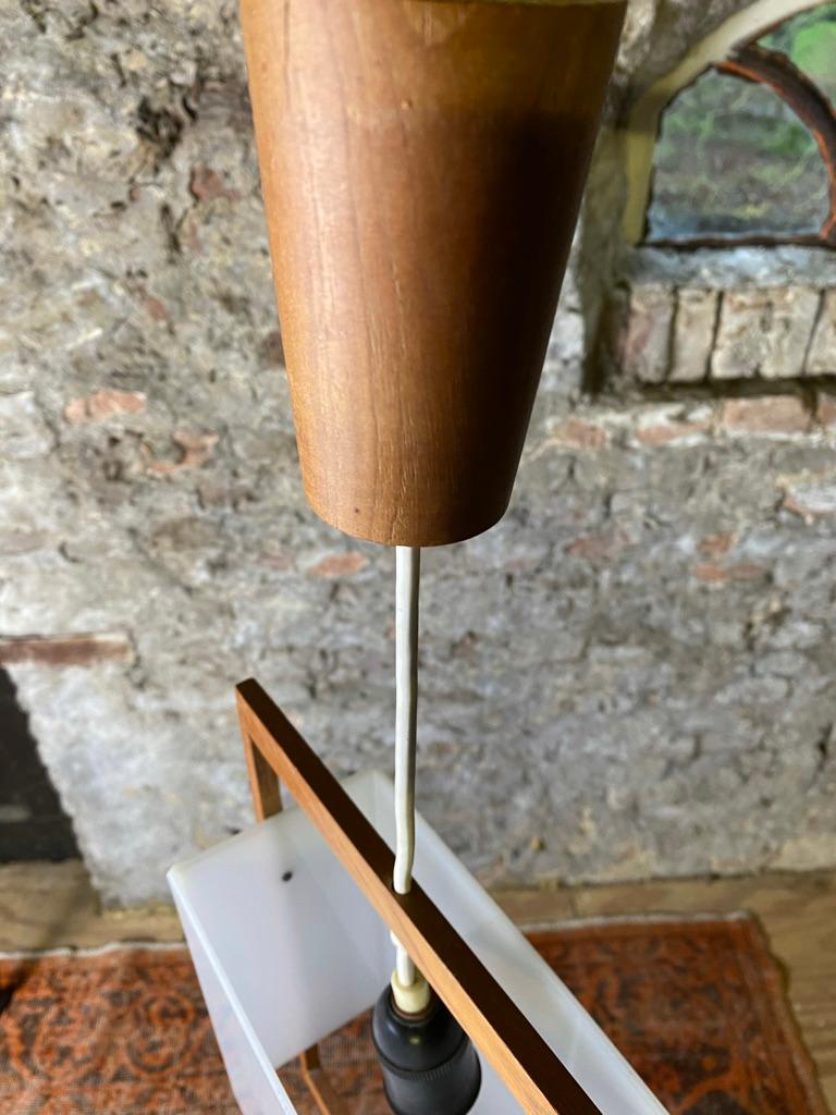 Beautiful small Danish teak en acrylic pendant lamp from the 60's . 
The lamp has an acrylic opal shade with a teak frame and ceiling rose. Very light weight so can be placed everywhere. E27 socket
Measurements: teak frame 36 cm x 22,5 cm acrylic