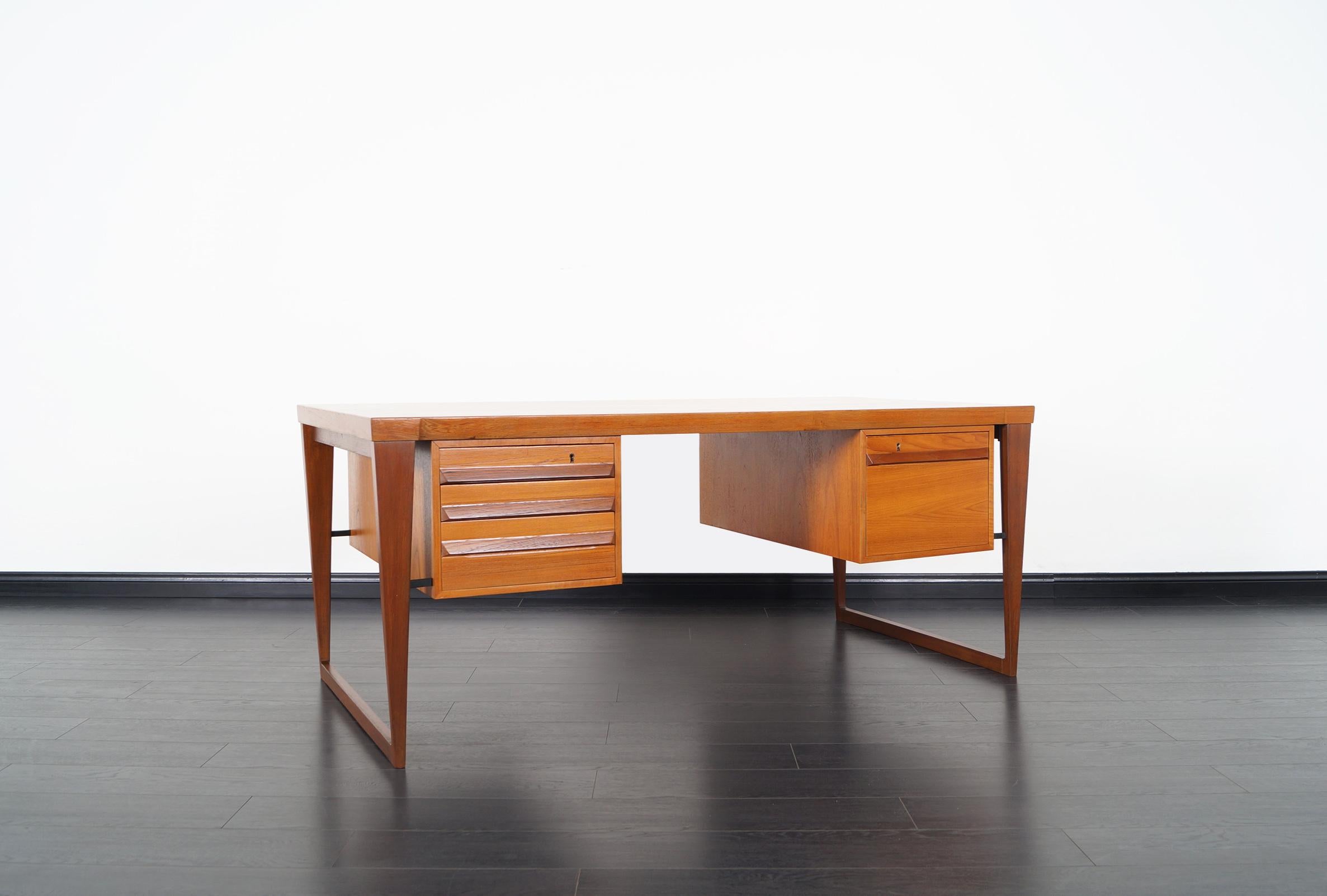 This rare sculptural freestanding executive desk was designed by Kai Kristiansen for Feldballes Møbelfabrik, model 70. Features two solid teak sled legs and contains three drawers on the left side and a file drawer to the right. On the opposite side