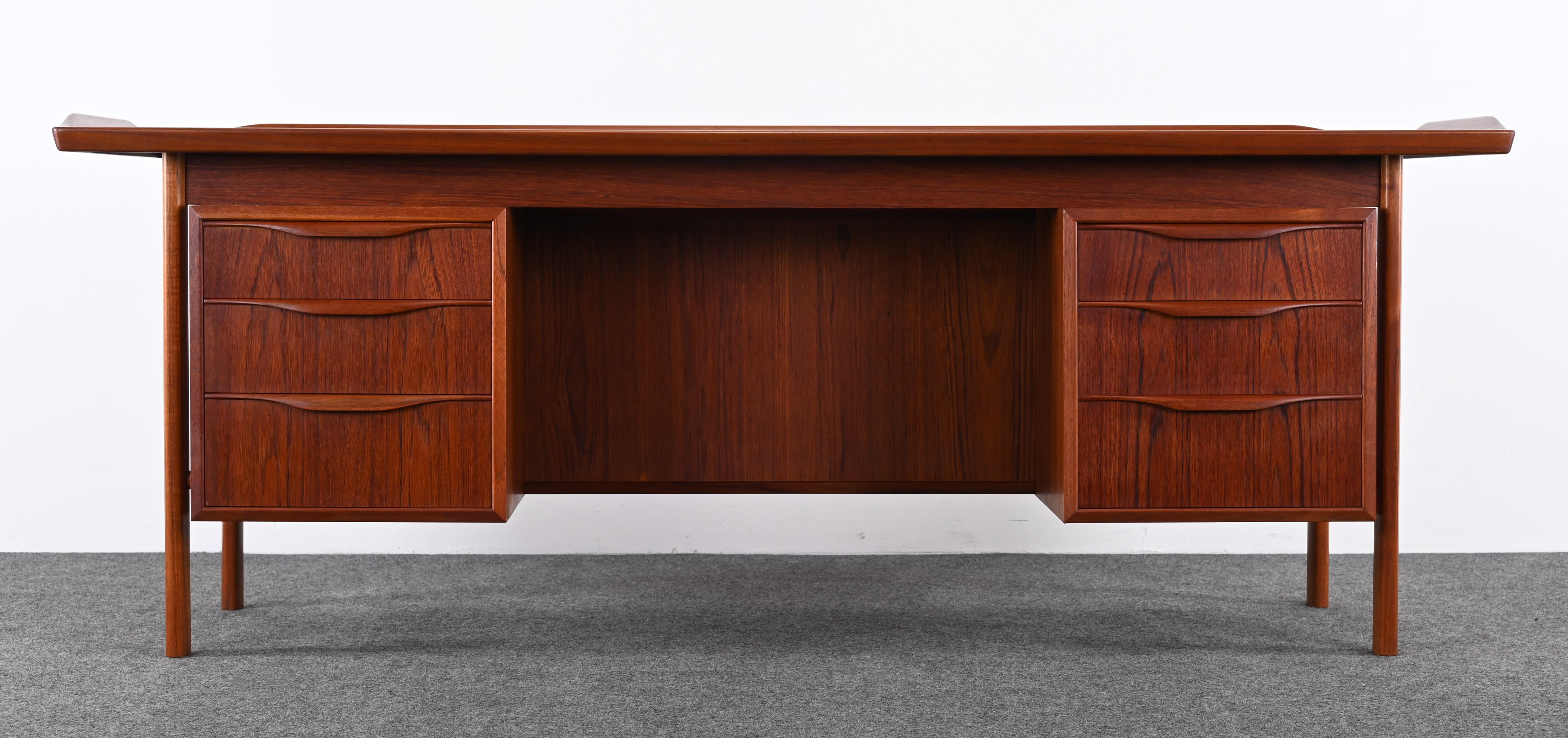 A handsome Danish Modern Executive Desk in the manner of Arne Vodder, 1960. This large Mid-Century desk has five drawers, shelves, and two drop-down doors with extra shelves for ample storage. It is difficult to find large-scale Danish Executive