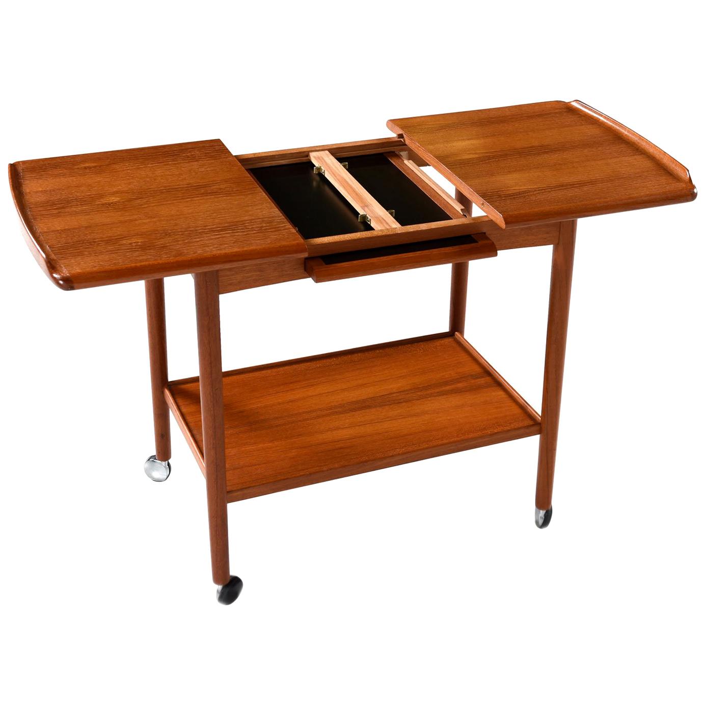 Scandinavian modern Danish teak bar cart by Dyrlund, circa 1960s, this extendable bar or tea cart is brilliant in both style and design. Pull open the expandable top to expose a black melamine top tray or leaf for serving beverages, protecting the
